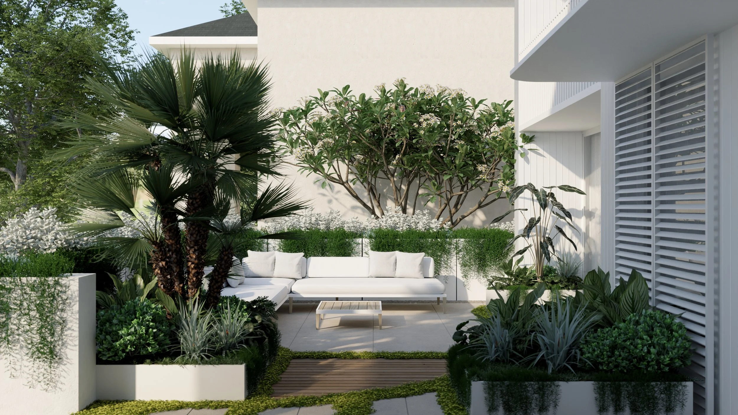 Modern outdoor patio area with white sofa, surrounded by lush greenery including trees and plants, with a small wooden table in front.