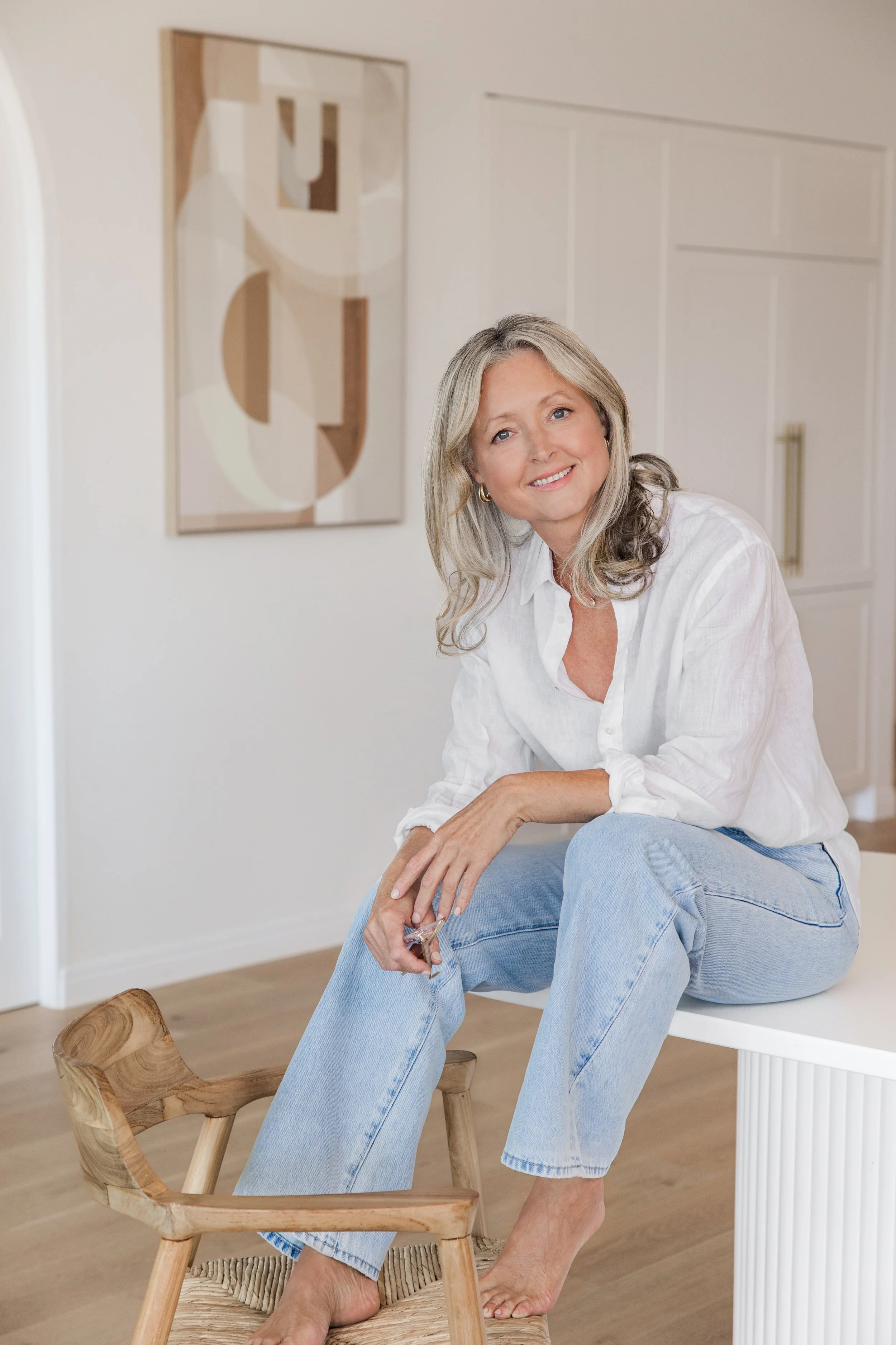 Anna Hutchins, clinical nutritionist, sitting barefoot in a bright, modern kitchen