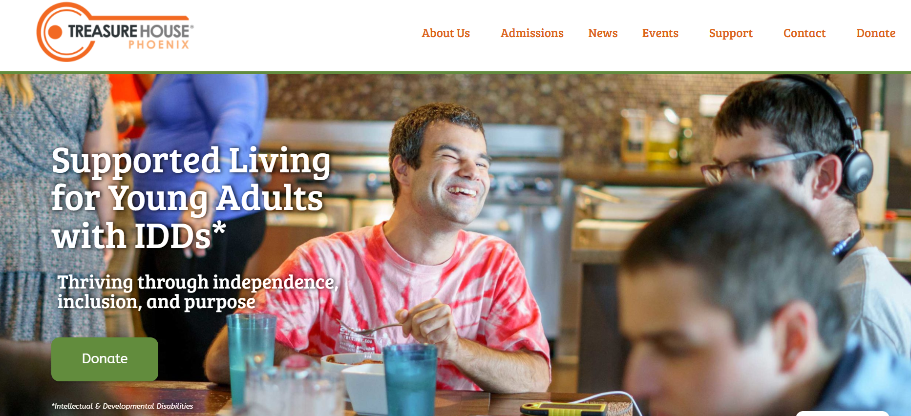 A group of young adults with intellectual and developmental disabilities enjoying a meal together at a cafe, smiling and engaging with each other.
