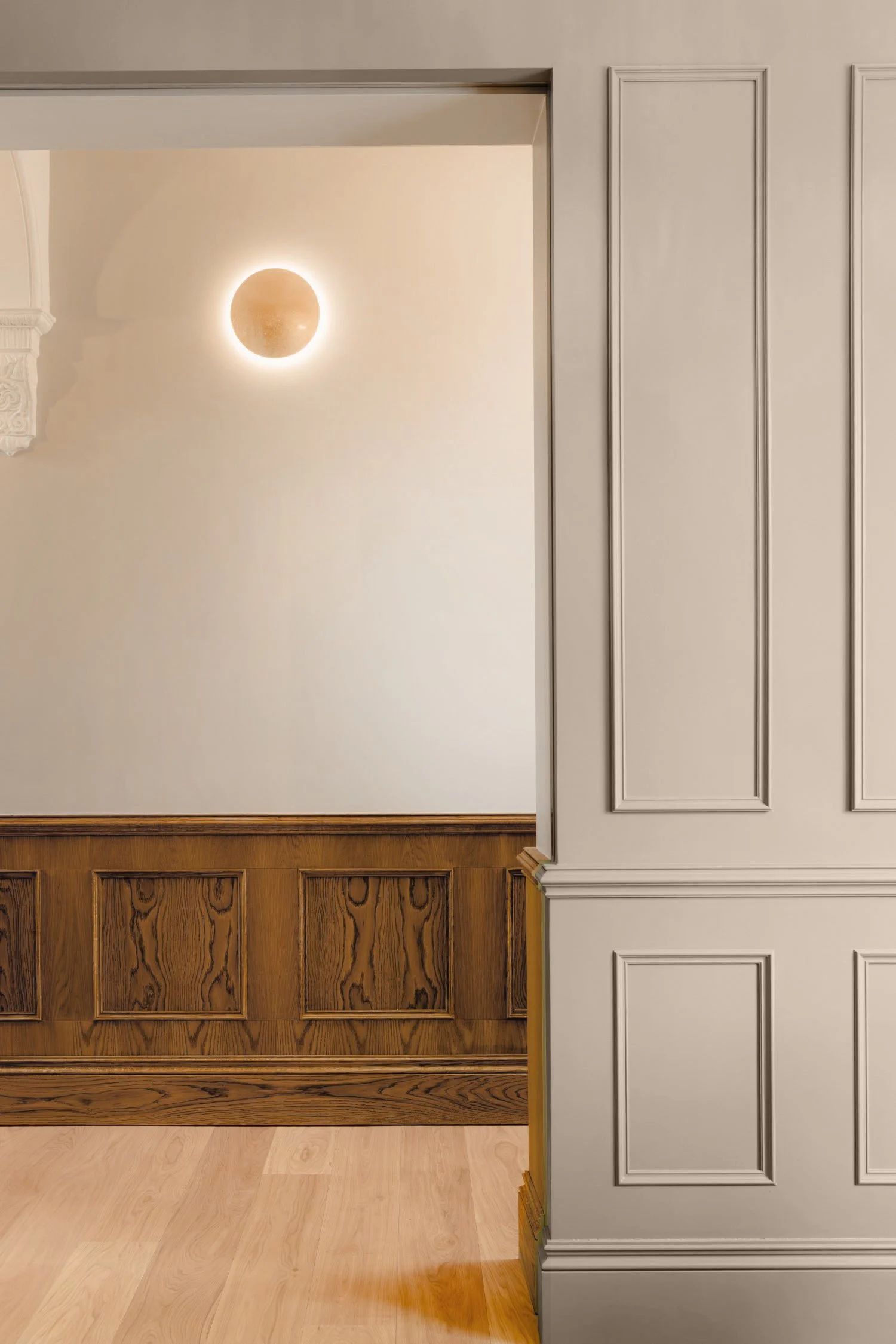 Interior room with white walls, wood paneling, and a decorated wall light.