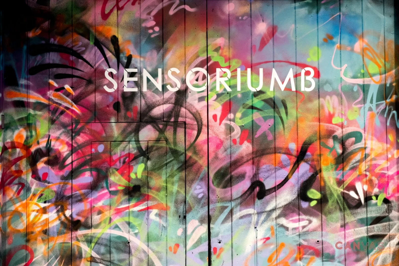 Colorful graffiti wall with the word 'SENSORIUMB' in white letters in the center.