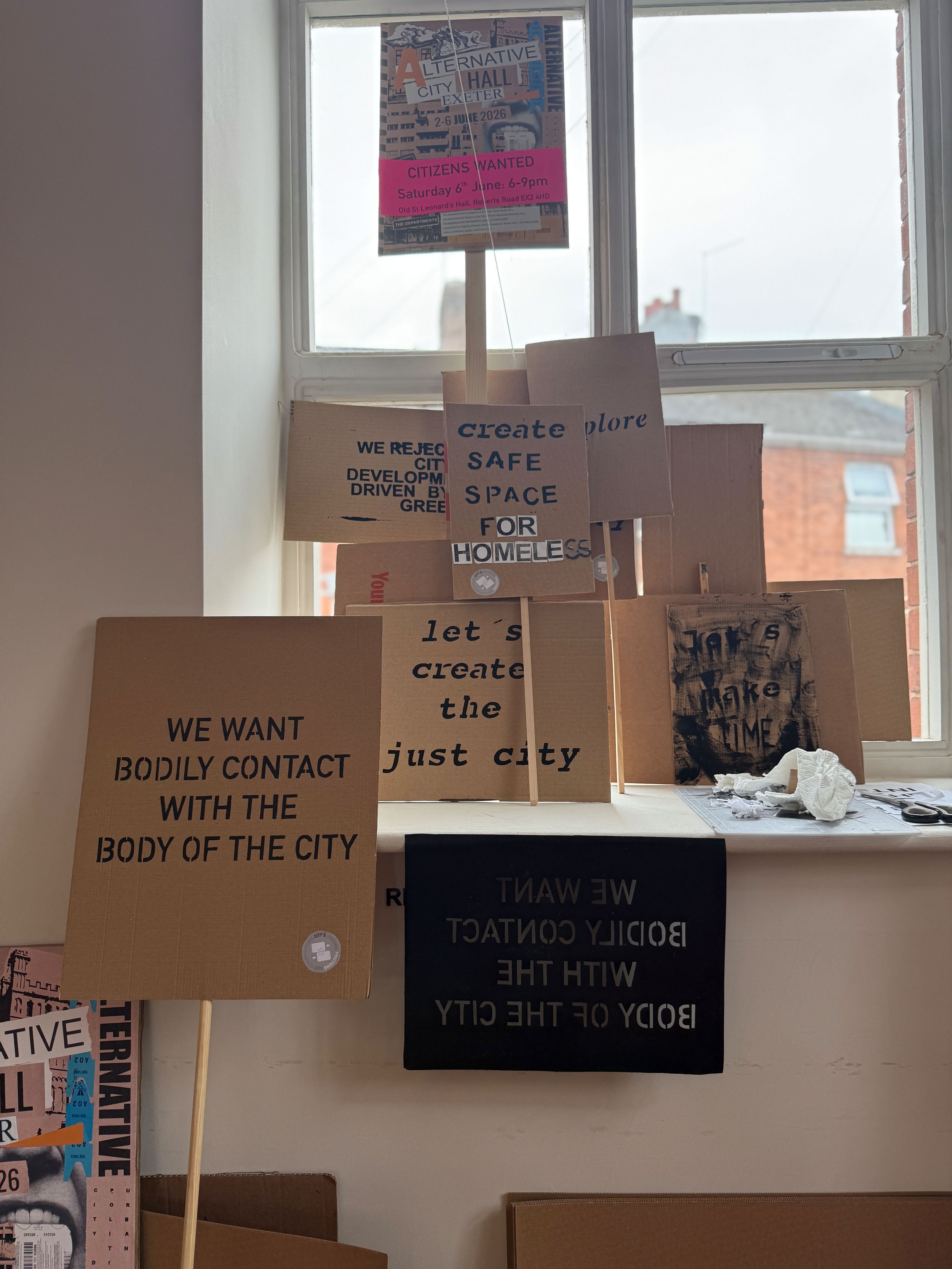 Signs and posters advocating for creating safe spaces within the city, with messages about rejecting bodily contact and building community.