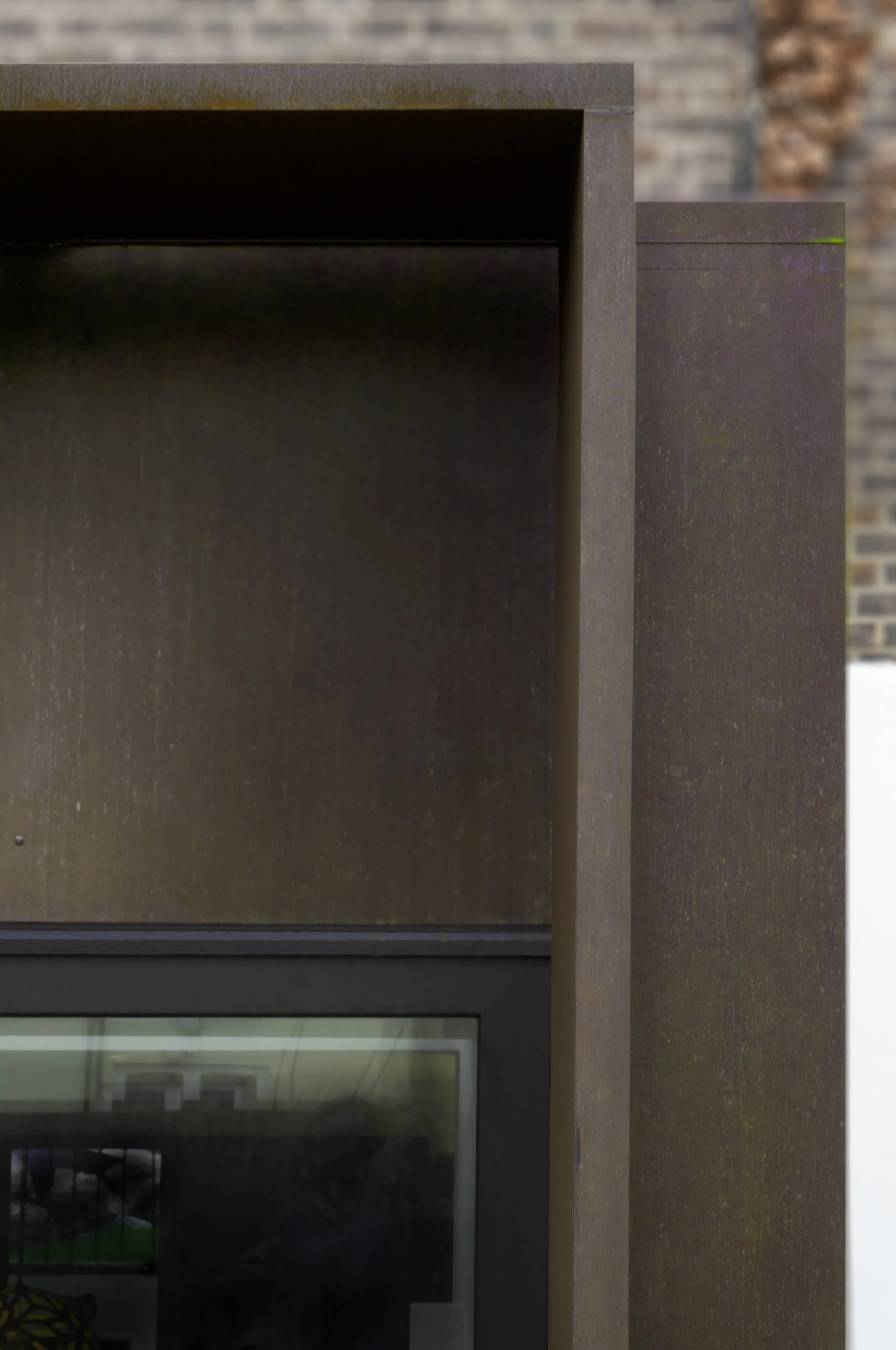 Close-up of a modern, dark-colored cabinet or display case with a glass panel, set against a brick wall background.