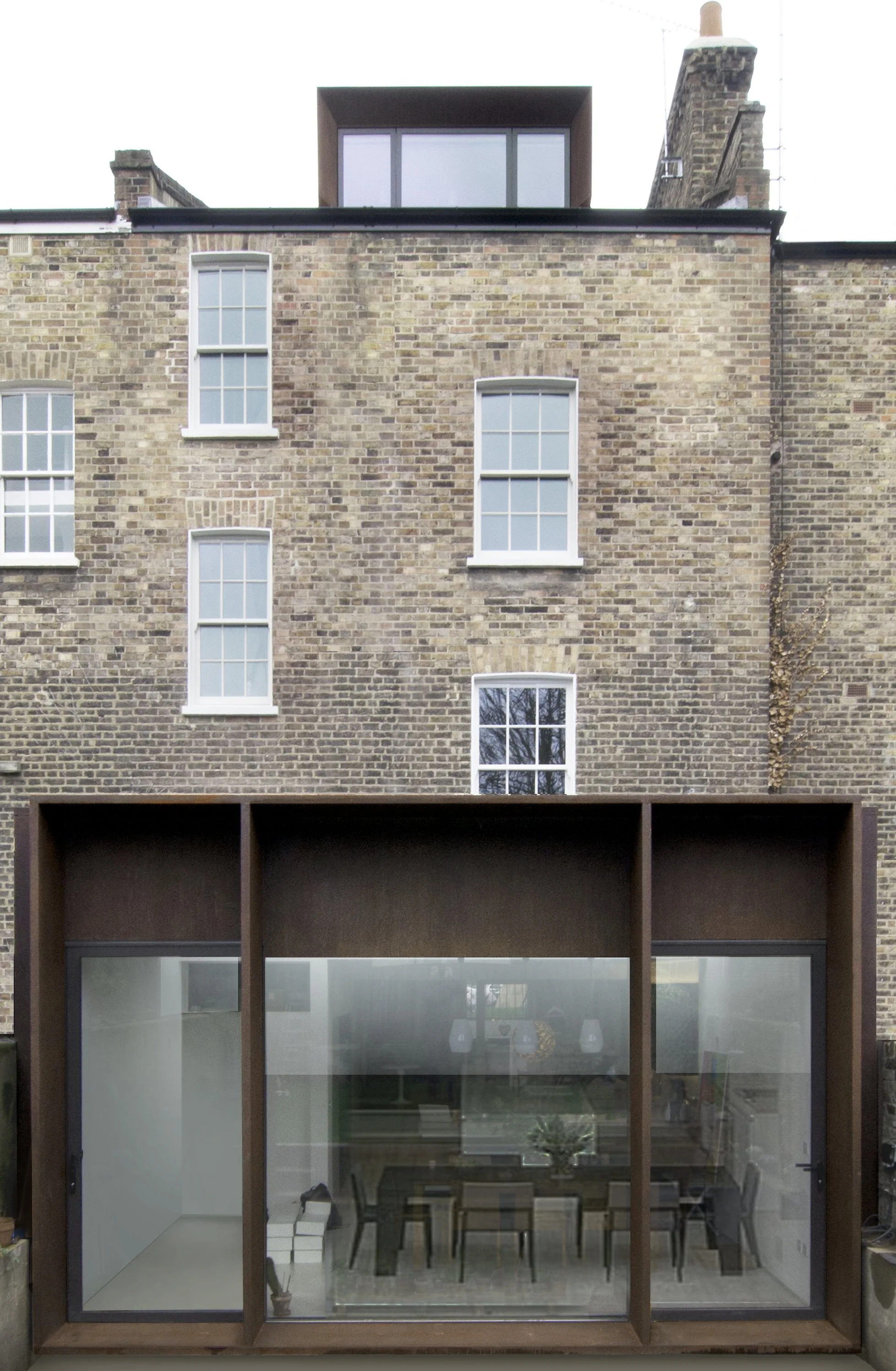 Modern extension with large glass windows on the ground floor, set against an older brick building with four vertically aligned sash windows.