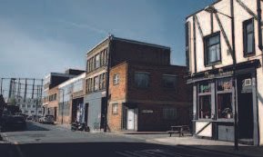 Street view of a row of old commercial buildings on a sunny day.