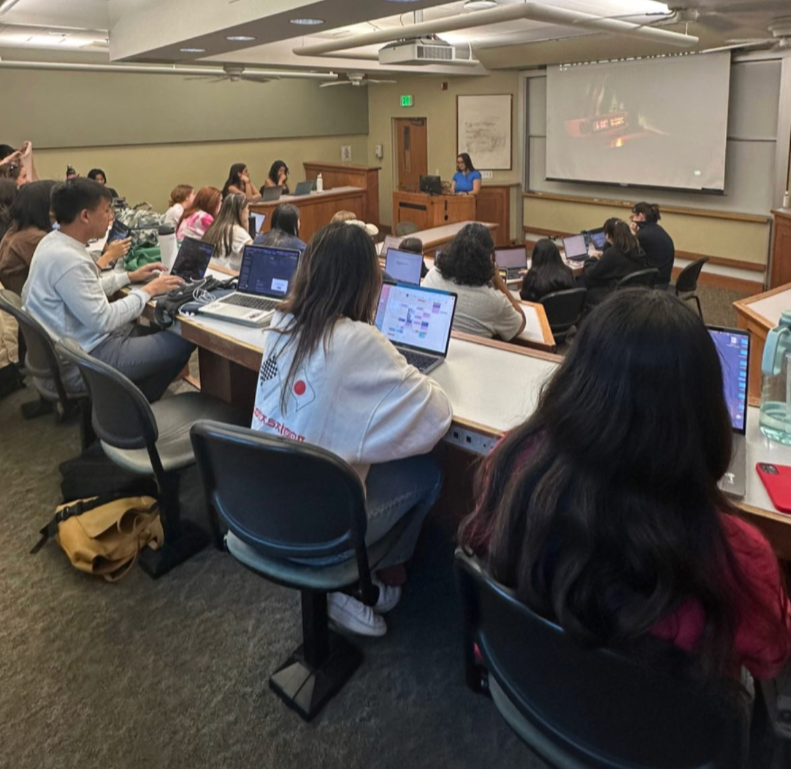 People in a classroom with computers open facing a speaker.