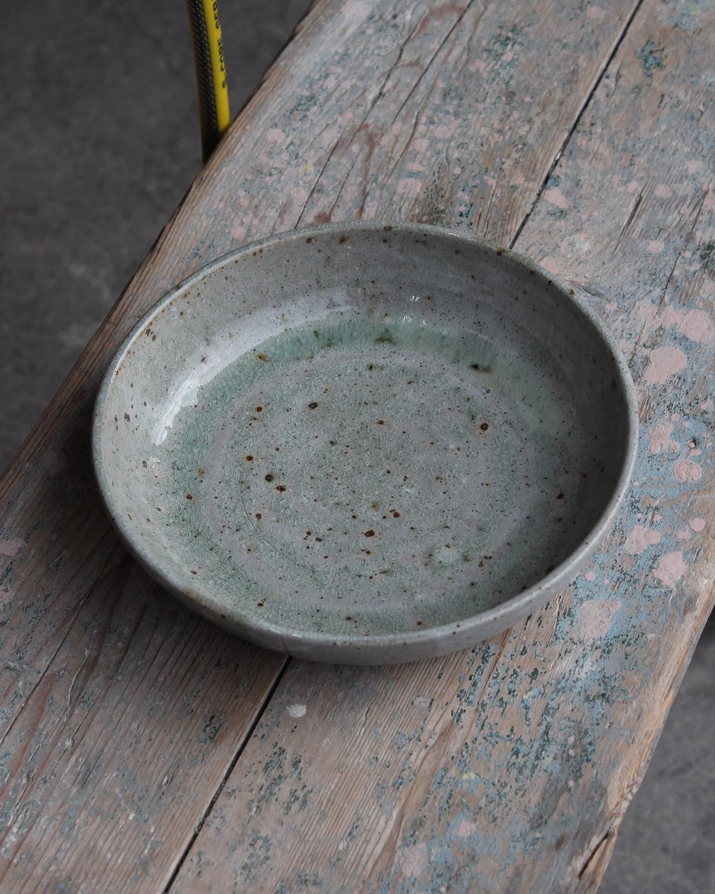 A ceramic bowl with a glazed interior sitting on a weathered wooden surface.