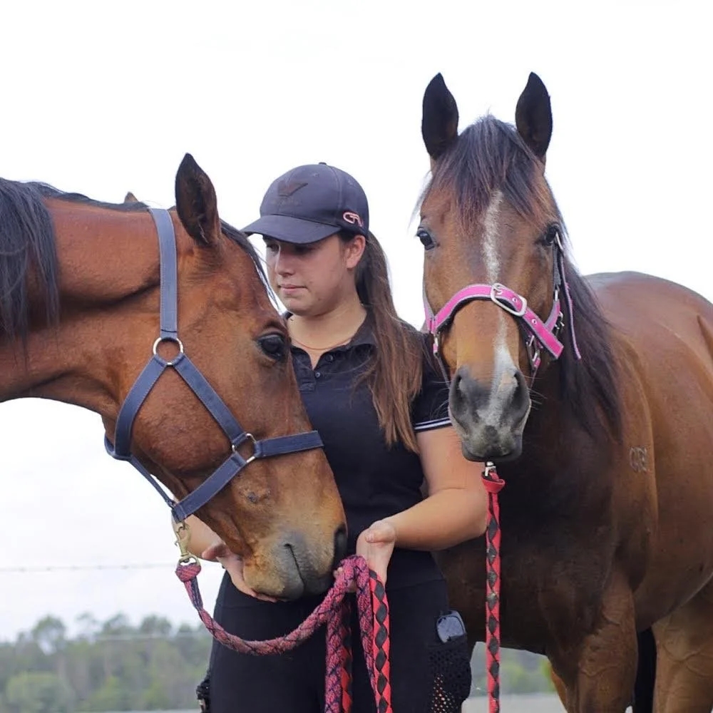 Standing with two horses at Migasoka Farm, sharing a quiet moment together in Queensland