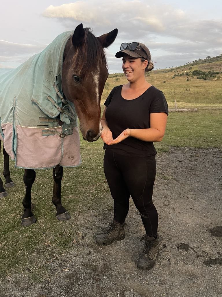 Standing with Frosty the horse at Migasoka Farm, wearing his blanket with dark skies in the background in Queensland
