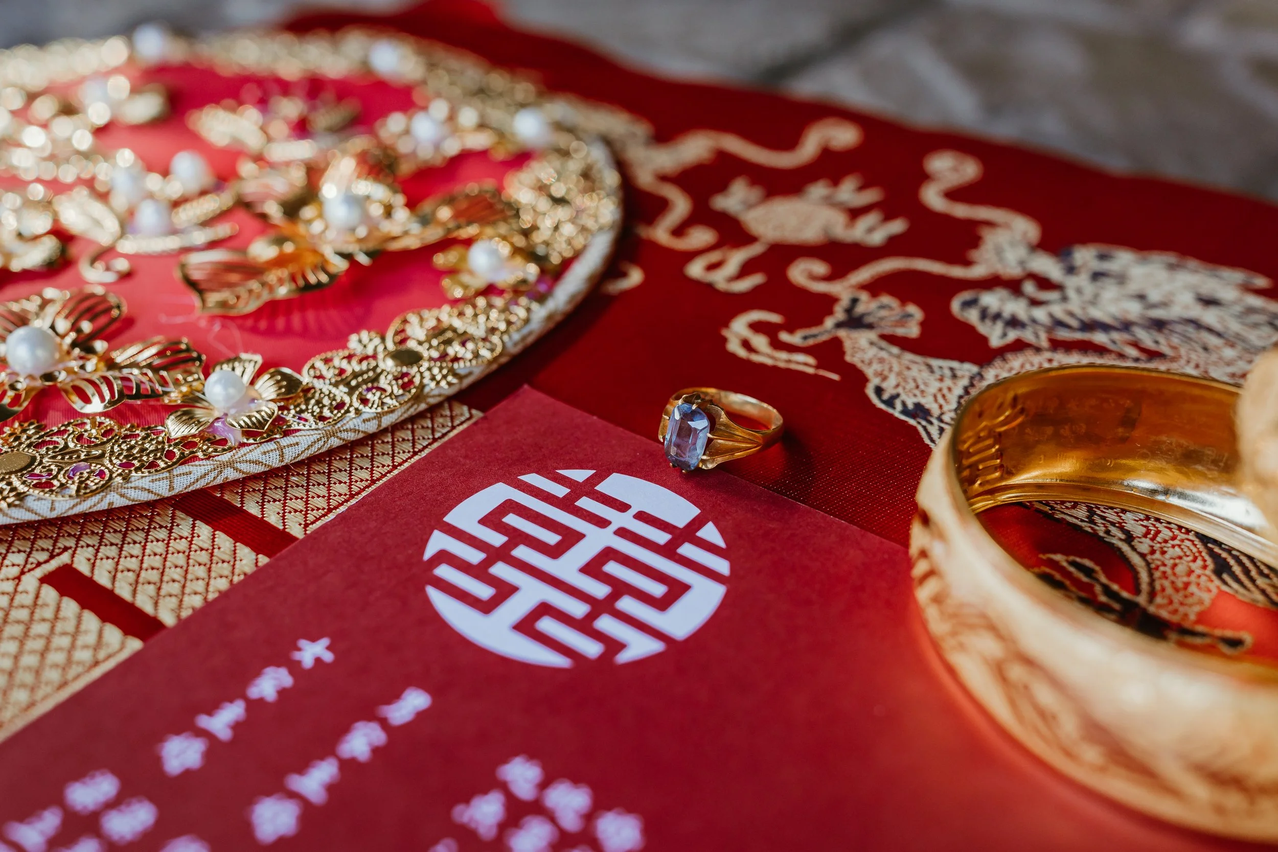 Jewelry and a ring placed on a red decorative cloth with a white and blue pattern