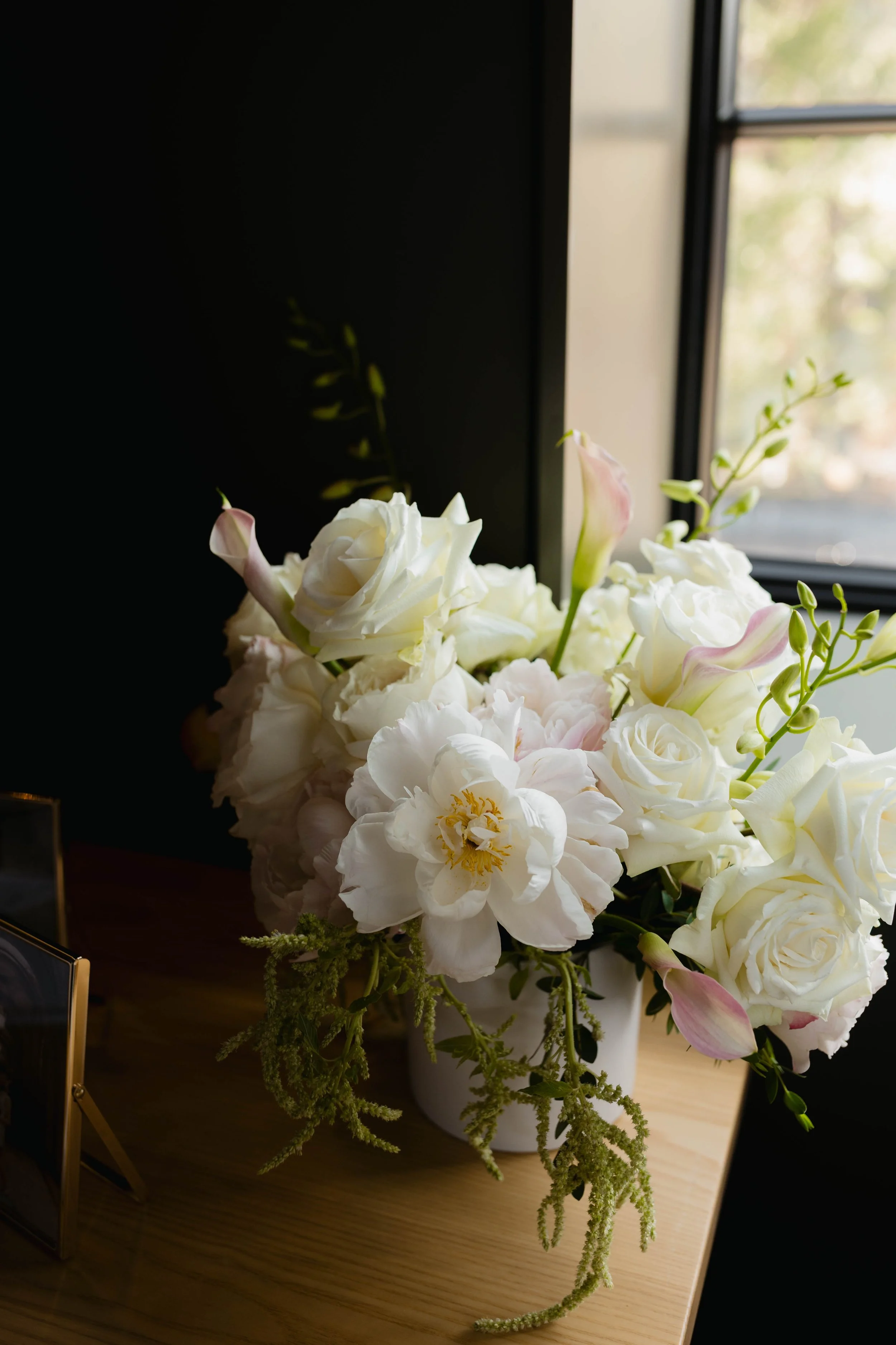 A wedding flower arrangement made by the wedding planner for the welcome table with roses peonies, amaranthus and calla lilies