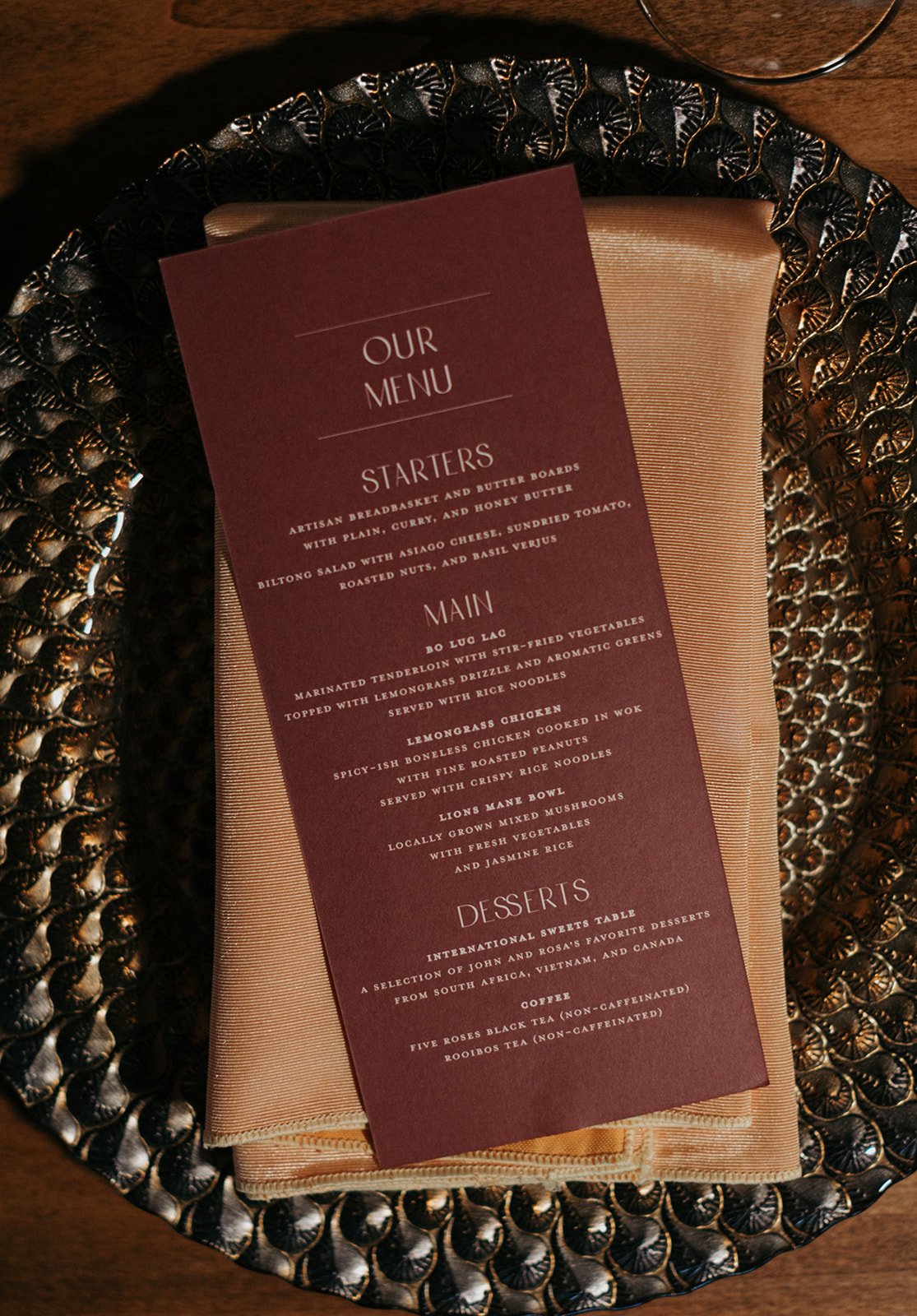 A restaurant menu card placed on a beige cloth napkin inside a decorative dark tray.