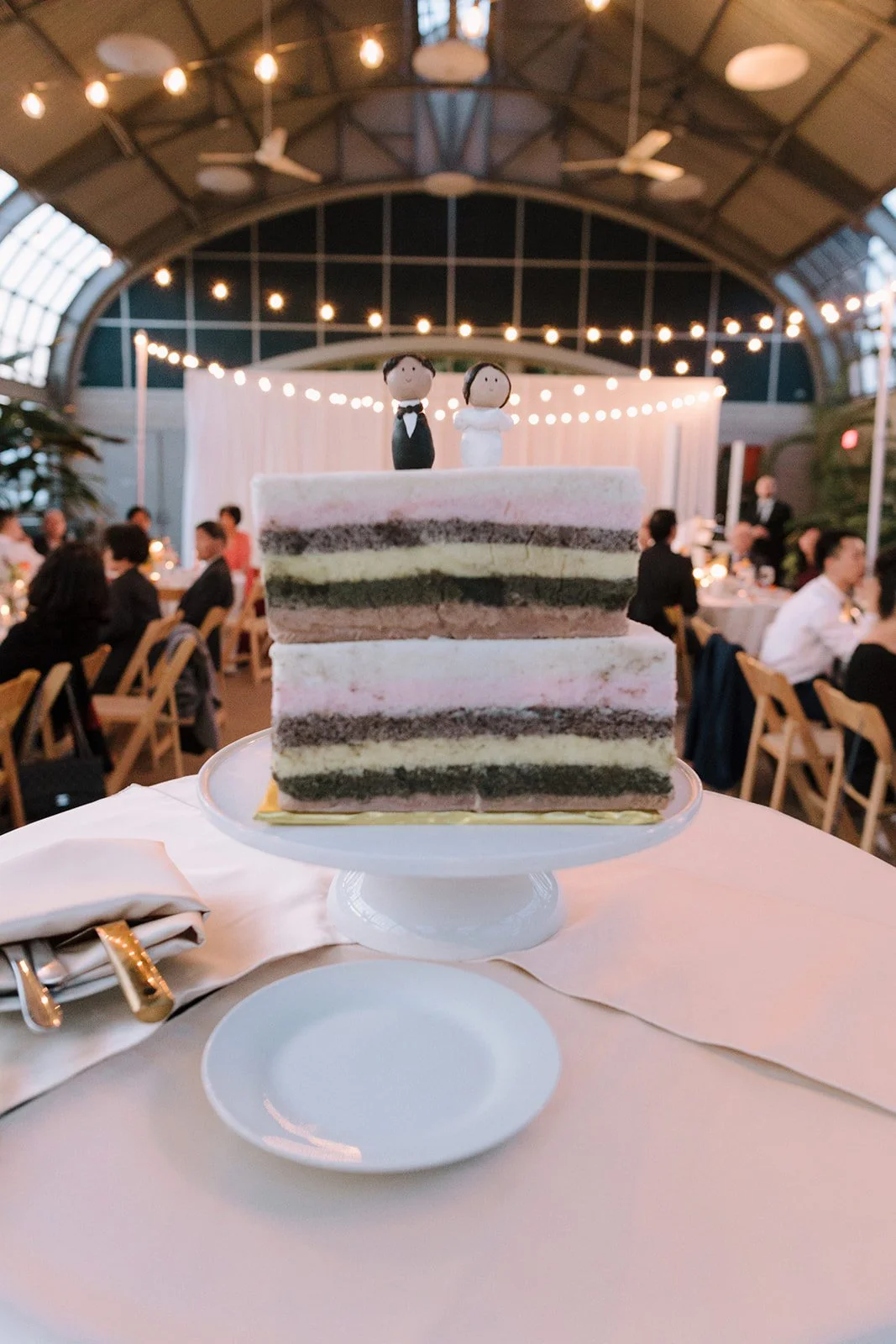 Wedding cake with groom and bride toppers at a wedding reception.