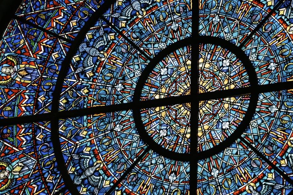 Close-up of a colorful stained glass window with complex geometric patterns and a circular design at the center.