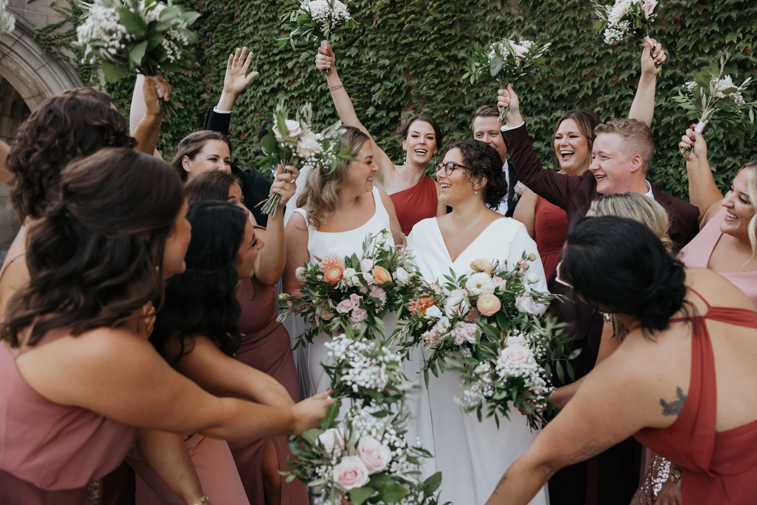 Group of people celebrating a wedding, holding bouquets and smiling.