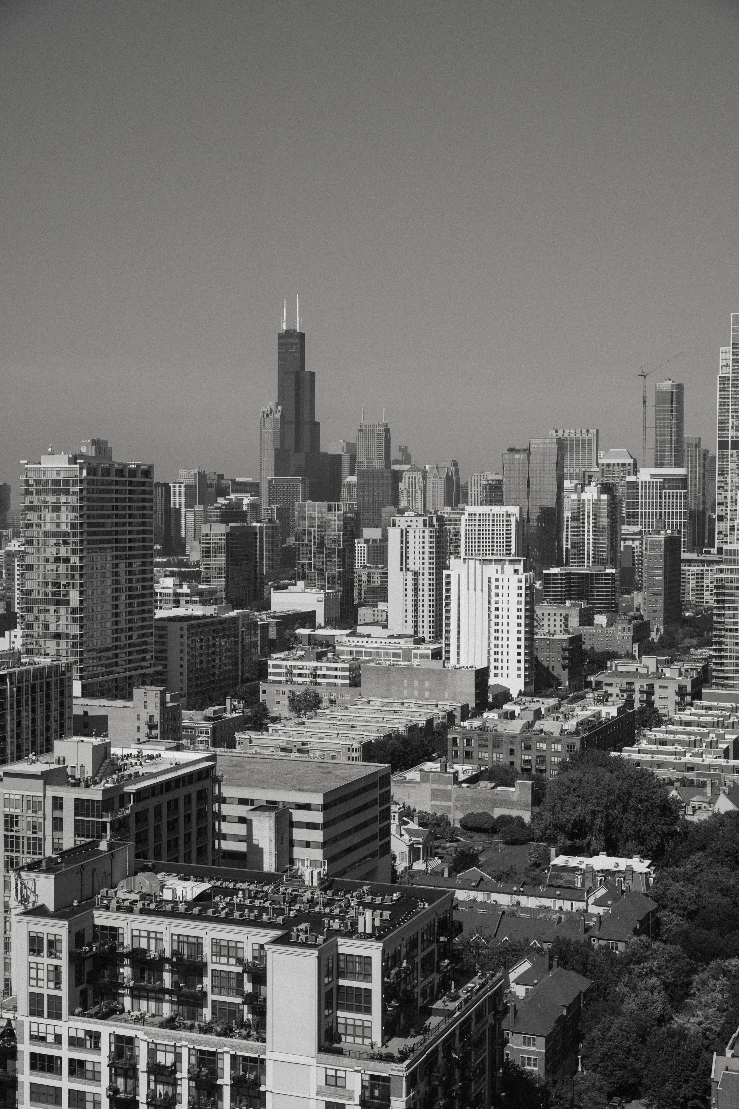 Black and white photo of a city skyline with various skyscrapers, including the Willis Tower, and residential buildings in the foreground.