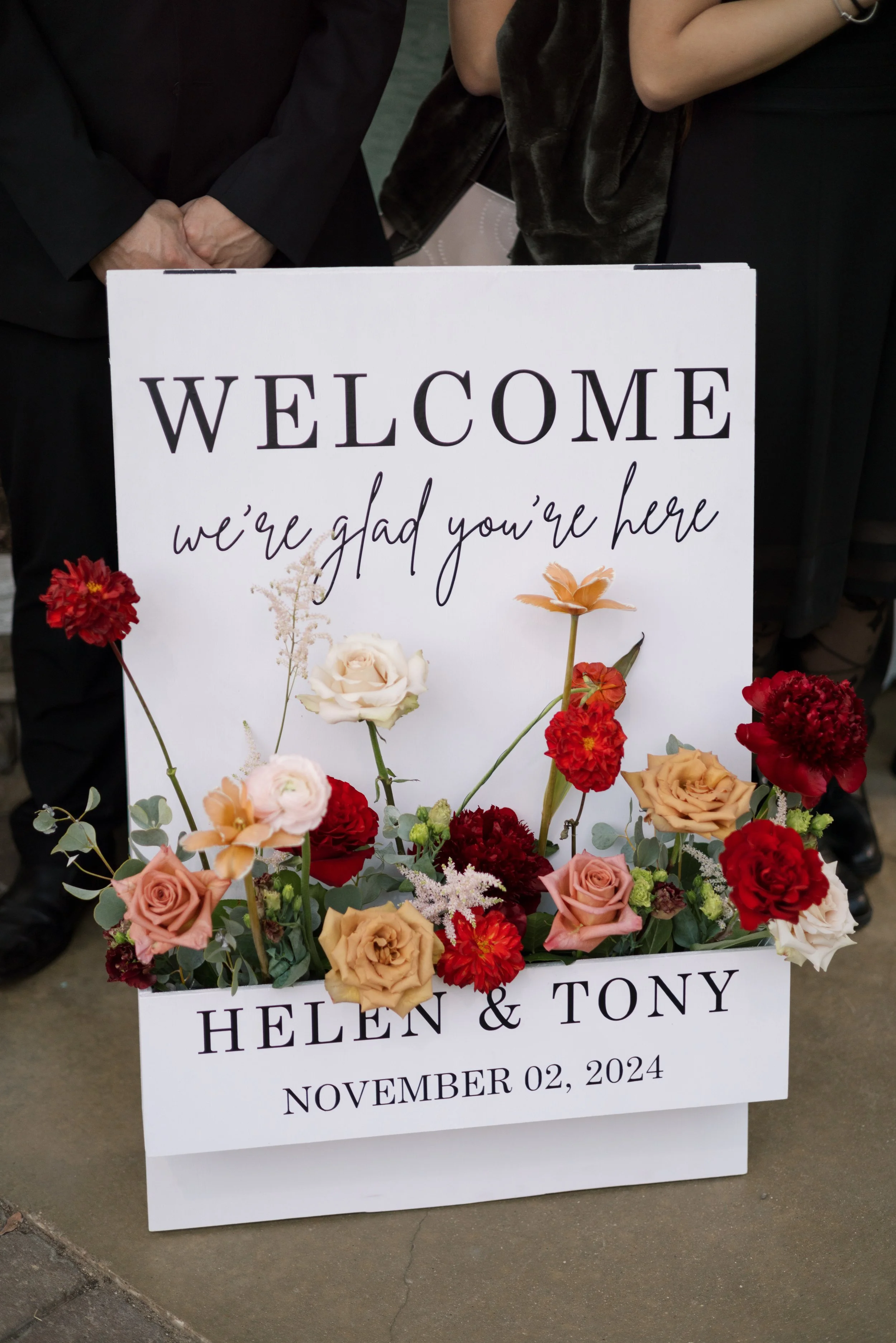 A wedding sign with flowers, welcoming guests to the wedding of Helen and Tony on November 02, 2024.