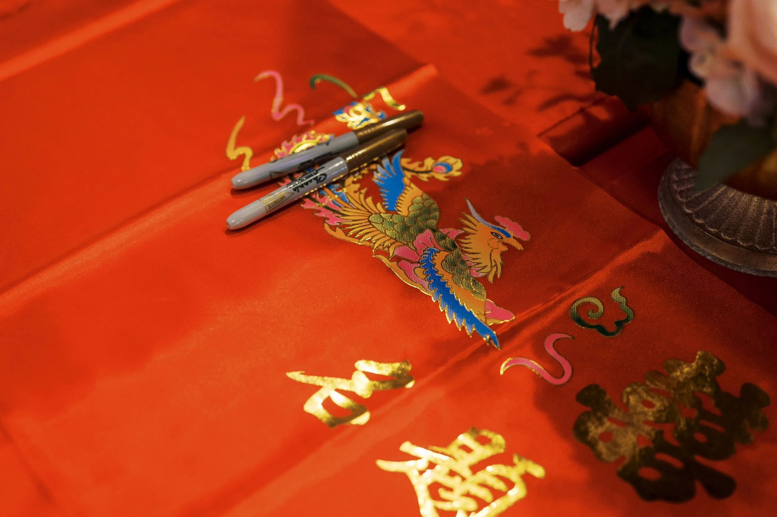 Red decorative paper featuring a colorful Chinese dragon illustration with gold accents, and two gray Sharpie markers resting on it.
