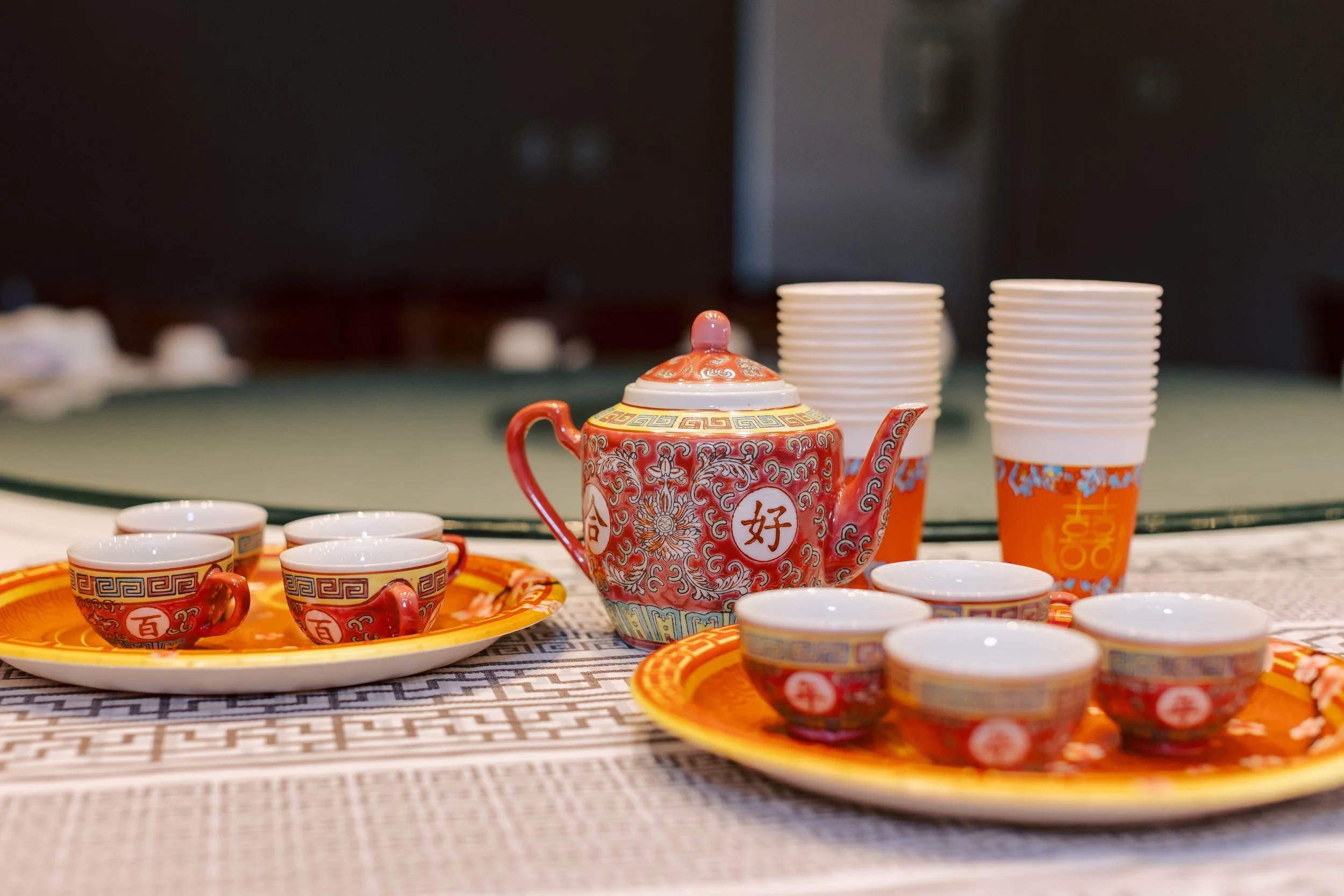 Colorful Chinese tea set on a table with stacked paper cups in the background.