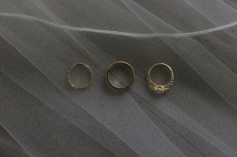 Three gold rings on a sheer fabric surface.