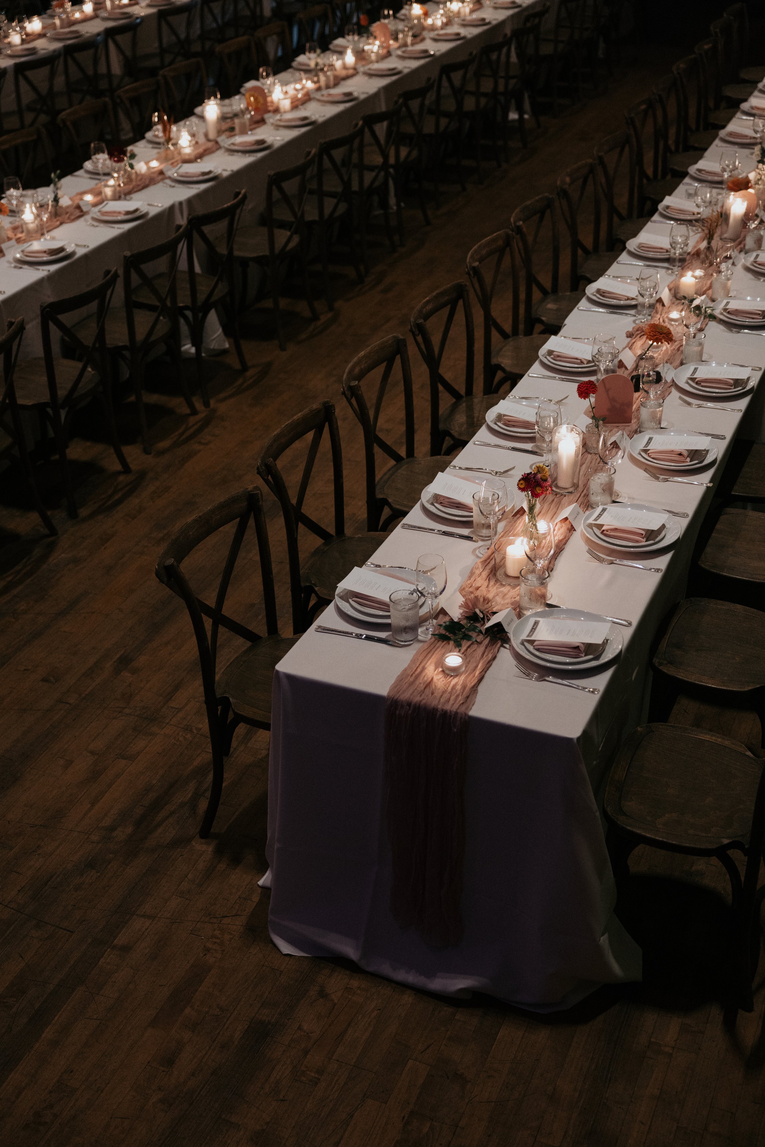 A long rectangular banquet table set for a formal dinner with candles and small flower arrangements.