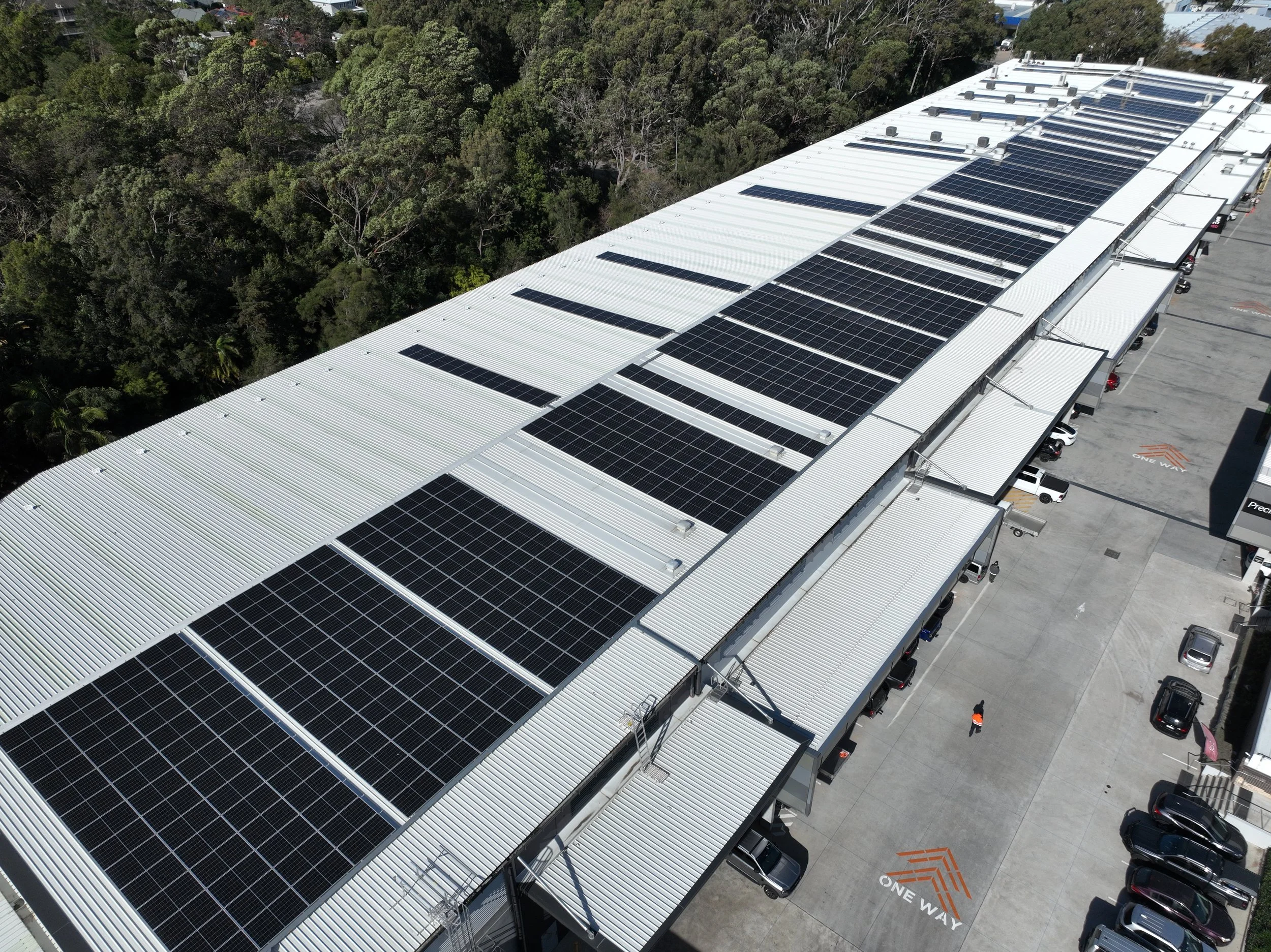 Aerial view of a large commercial building with solar panels installed by Kennedys