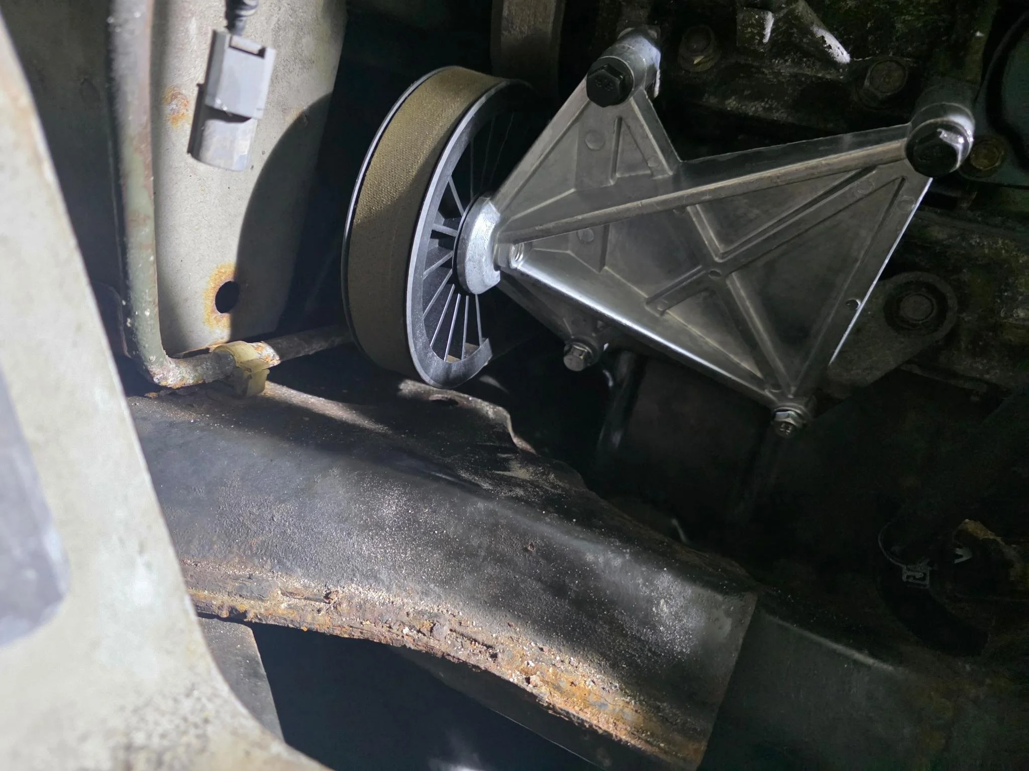 Close-up of a pulley and metallic housing with bolts showing the successful removal of the 2007 Honda Accord airconditioning compressor.