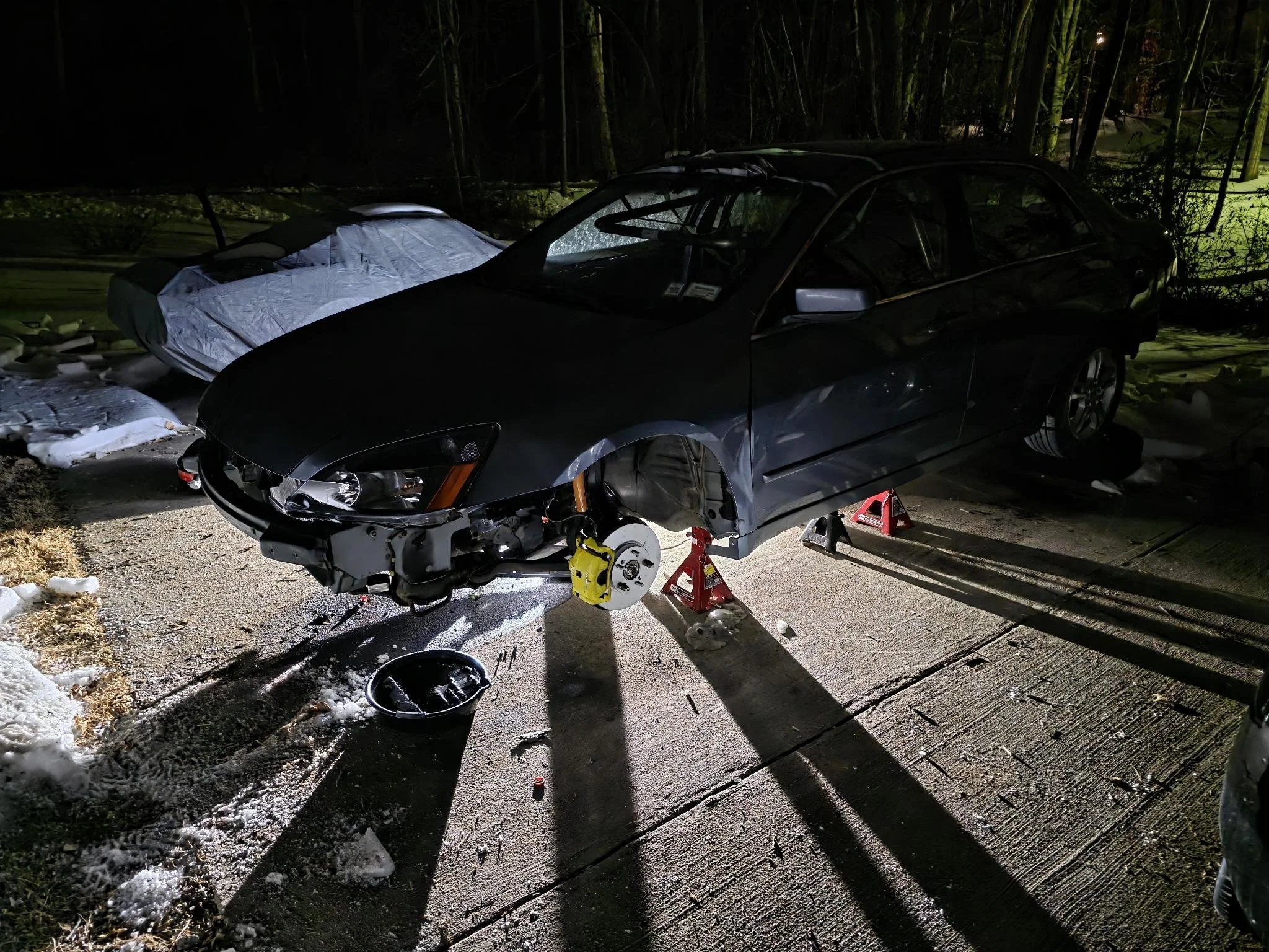 2007 Honda Accord, supported by jack stands, at night showing work in progress as the team builds an endurance racing car.