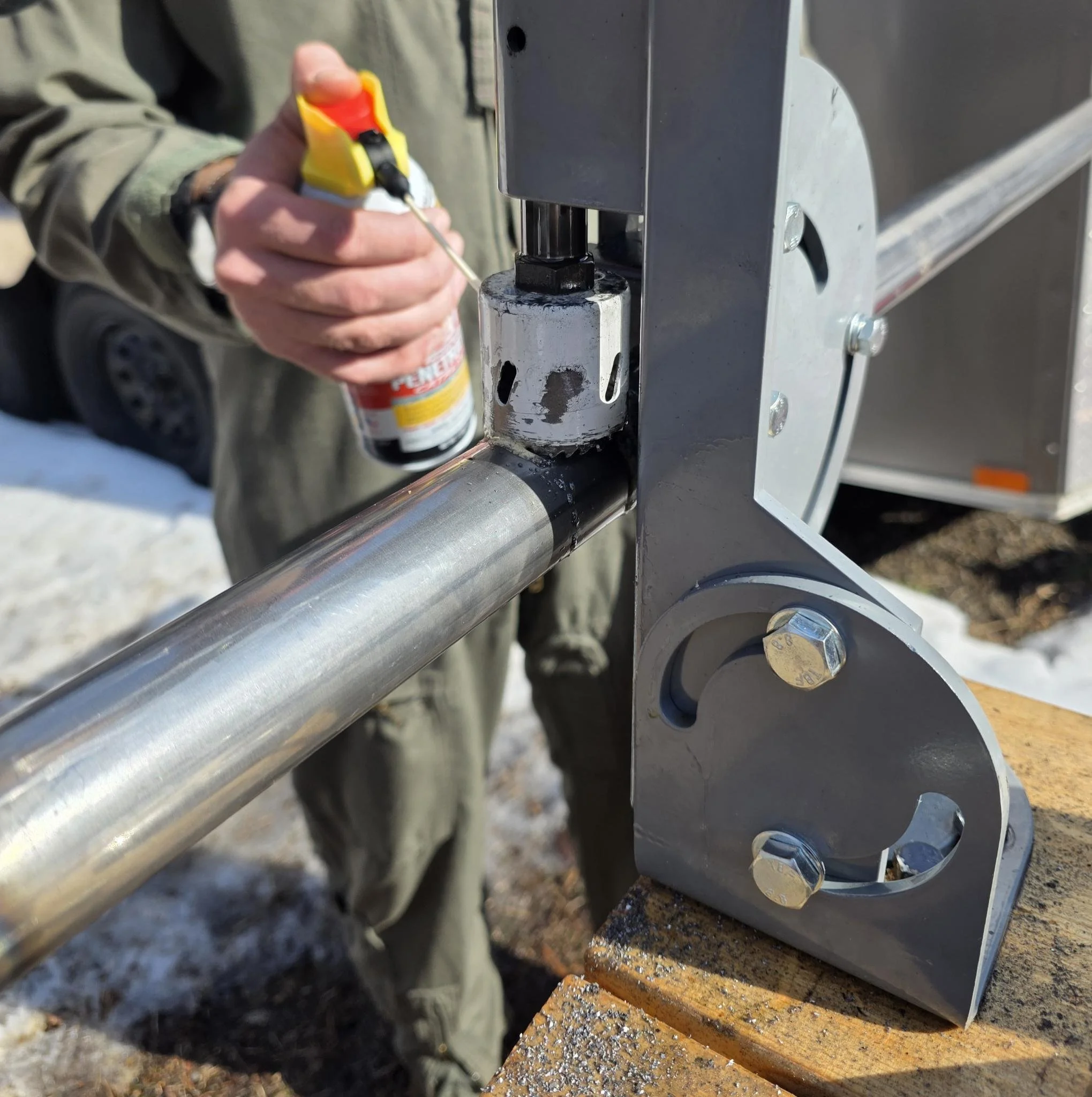 A person using a tool to apply a lubricant to a metal pipe as it was cut in preparation for the roll cage