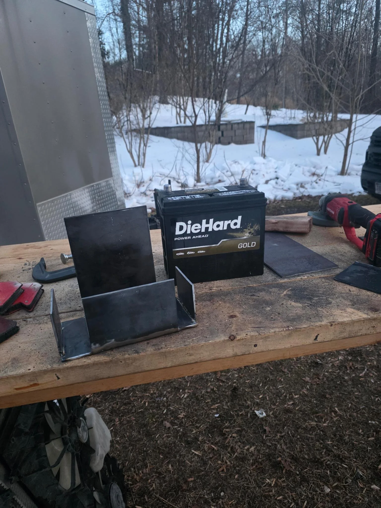 A workbench with a DieHard Gold car battery, metal brackets, custom battery box for 2007 Honda Accord