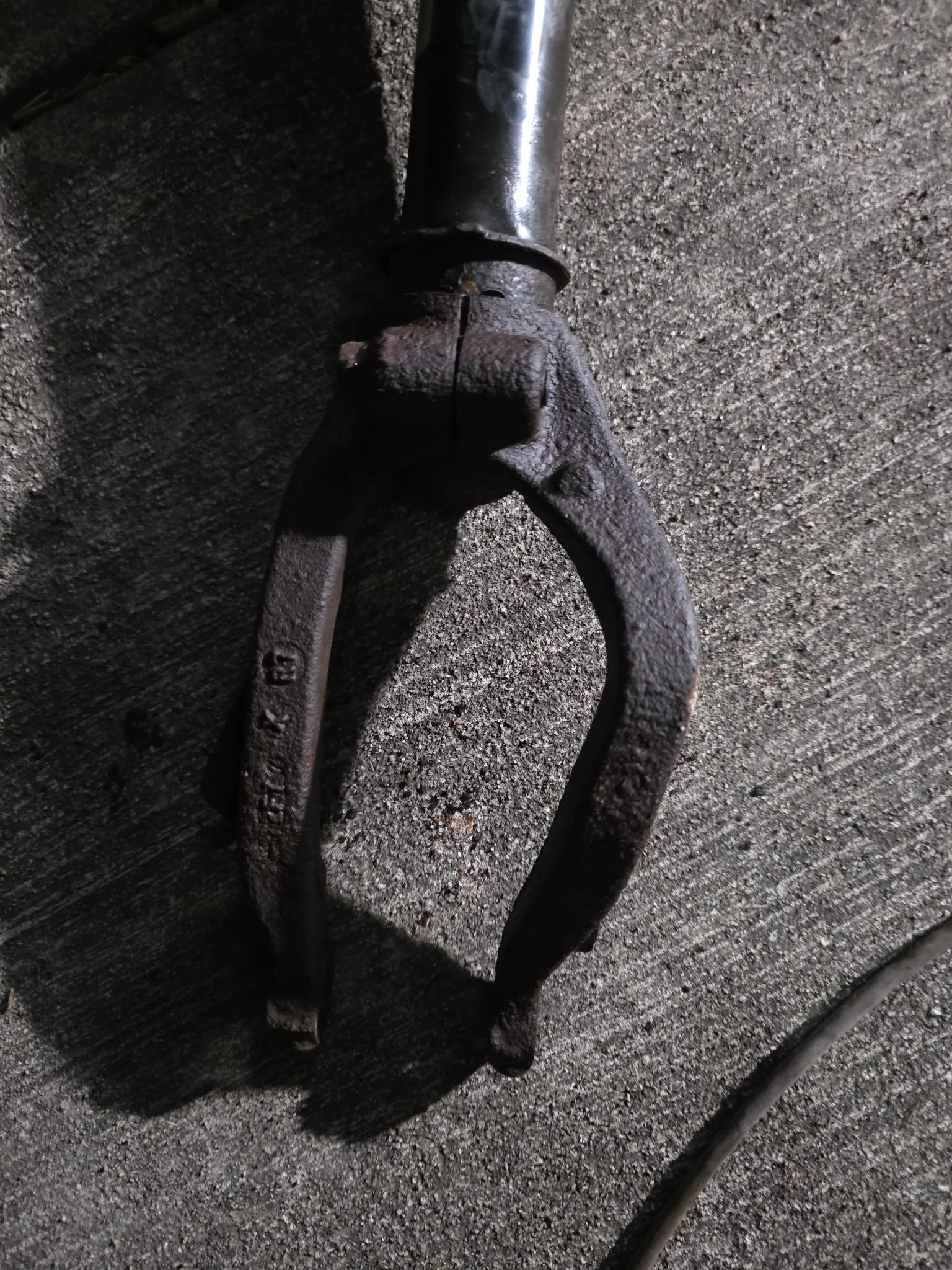 Close-up of a 2007 Honda Accord rusty metal fork attached to a mechanical component on a concrete surface.