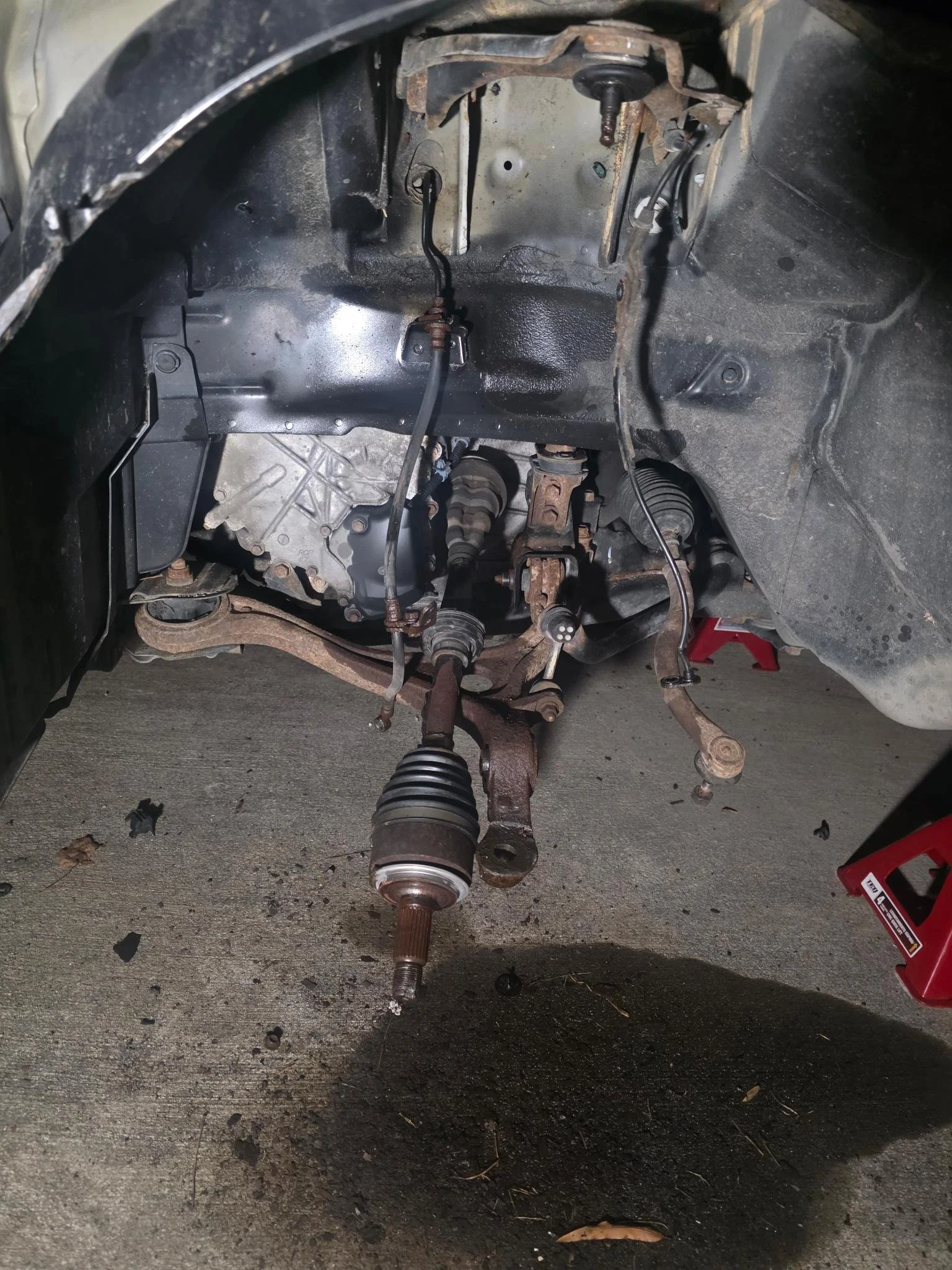 The image shows the front suspension and steering components of a car, with the wheel removed. Visible parts include the steering rack, tie rods, control arms, and the CV axle for 2007 Honda Accord.