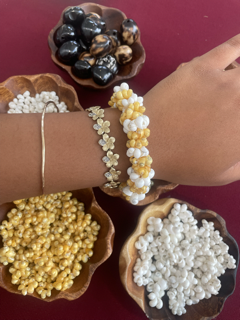 Display of jewelry and bowls of small beads or candies on a dark red surface, with a hand showing bracelet and ring.