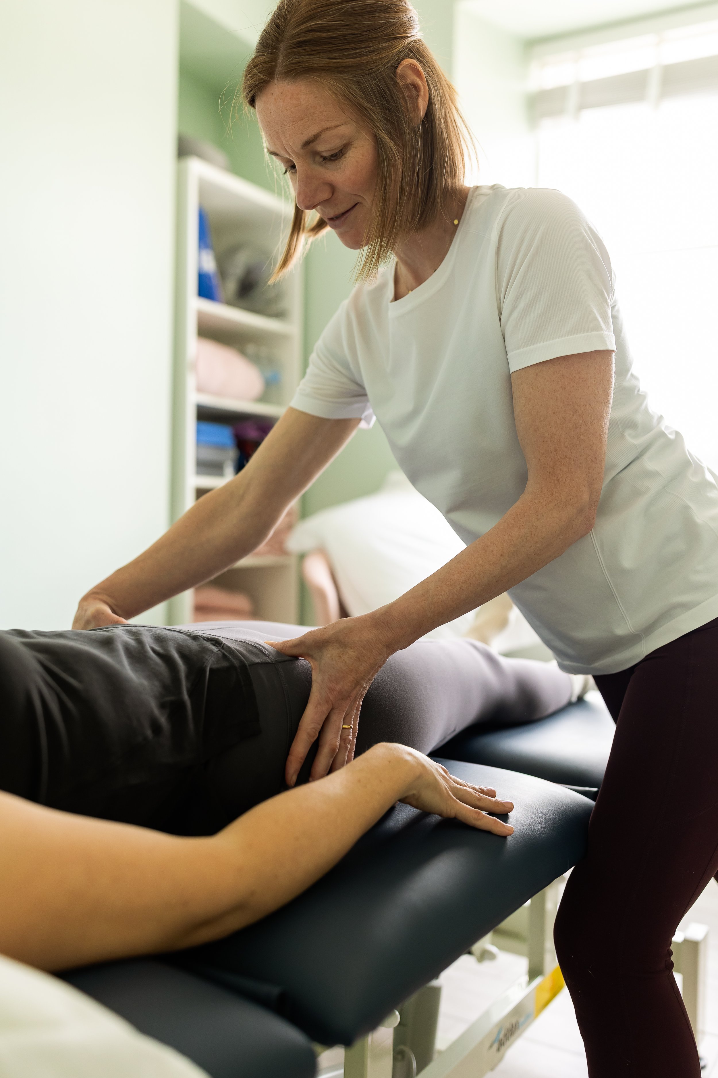 Jenny assessing a client’s hip and movement during a hands-on rehabilitation session at Core Pilates Oban.