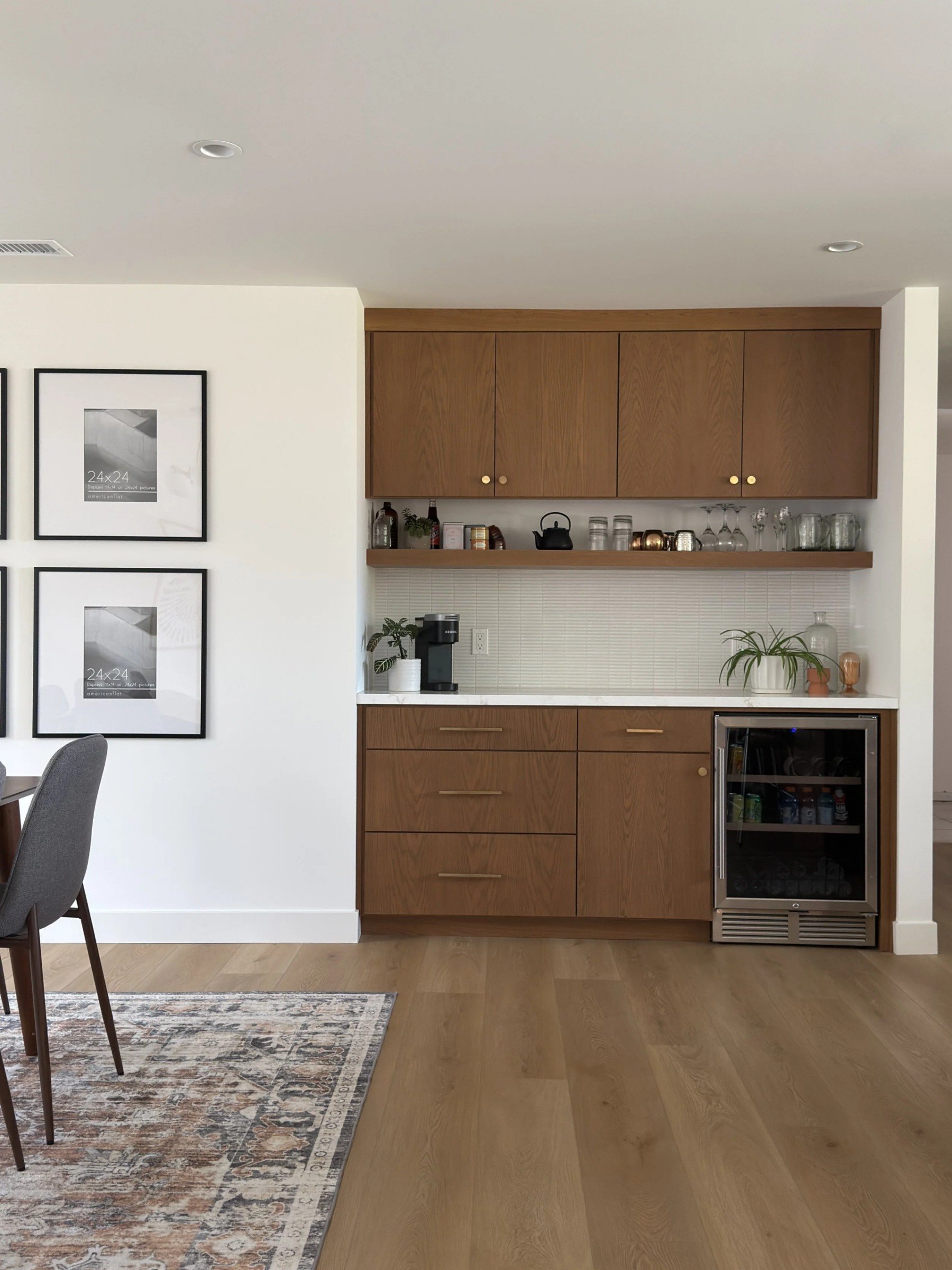 Kitchen bar area with wooden cabinets, a mini fridge, a coffee maker, and decorative plants on the counter.