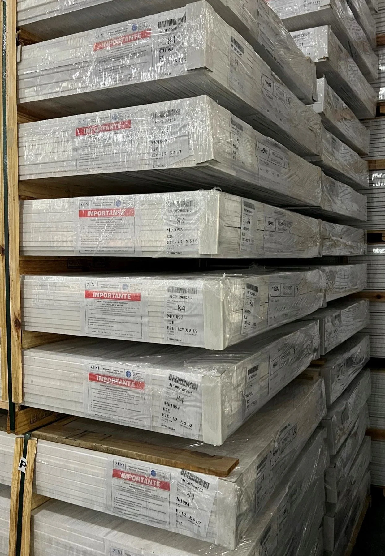 Stacks of pine moulding primed wrapped in plastic, stored on wooden pallets in a sawmill ready for exporting