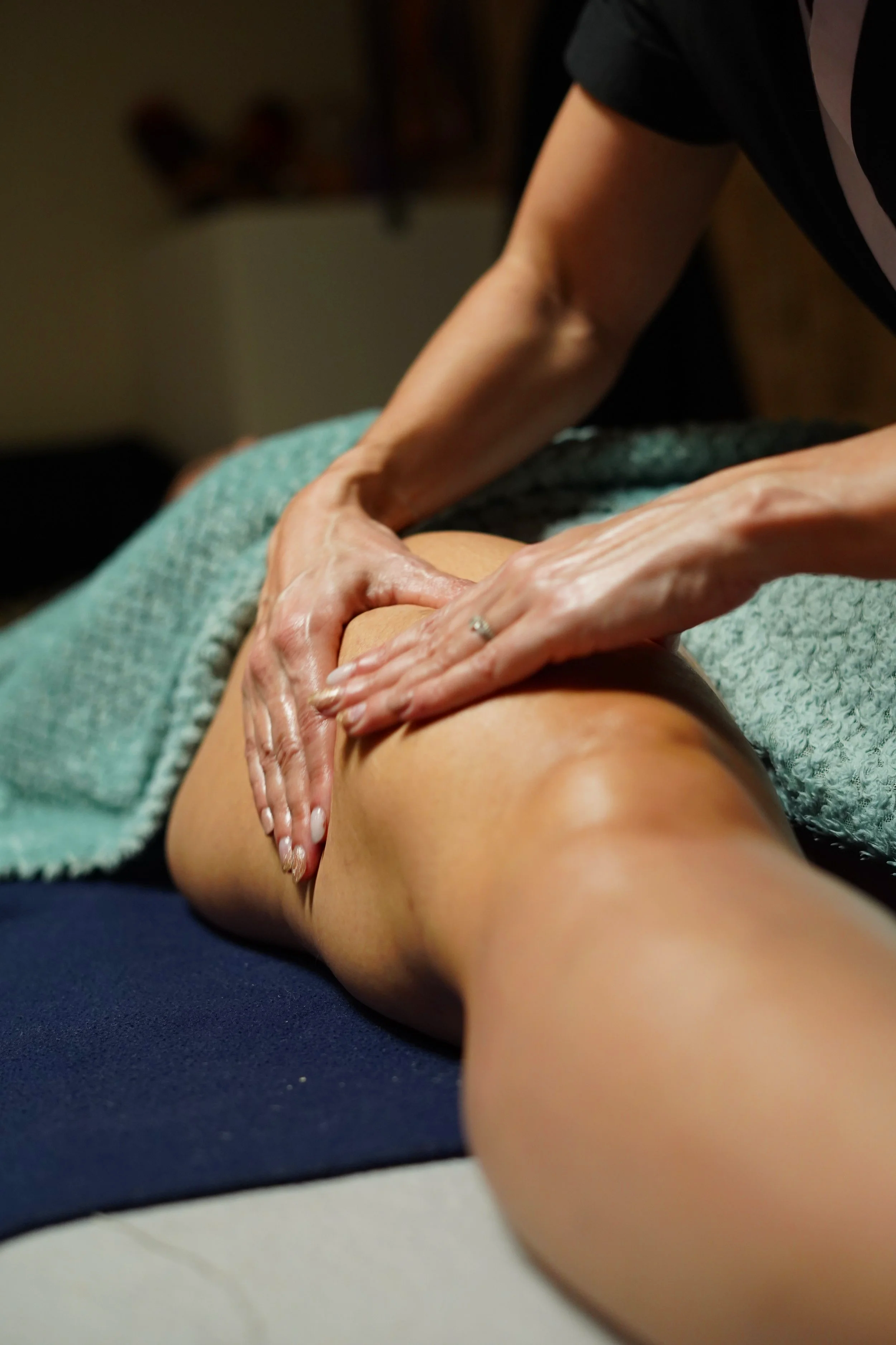 Une personne reçoit un massage ou une séance de physiothérapie sur la cuisse d'une autre personne, avec des mains utilisées pour la manipulare.