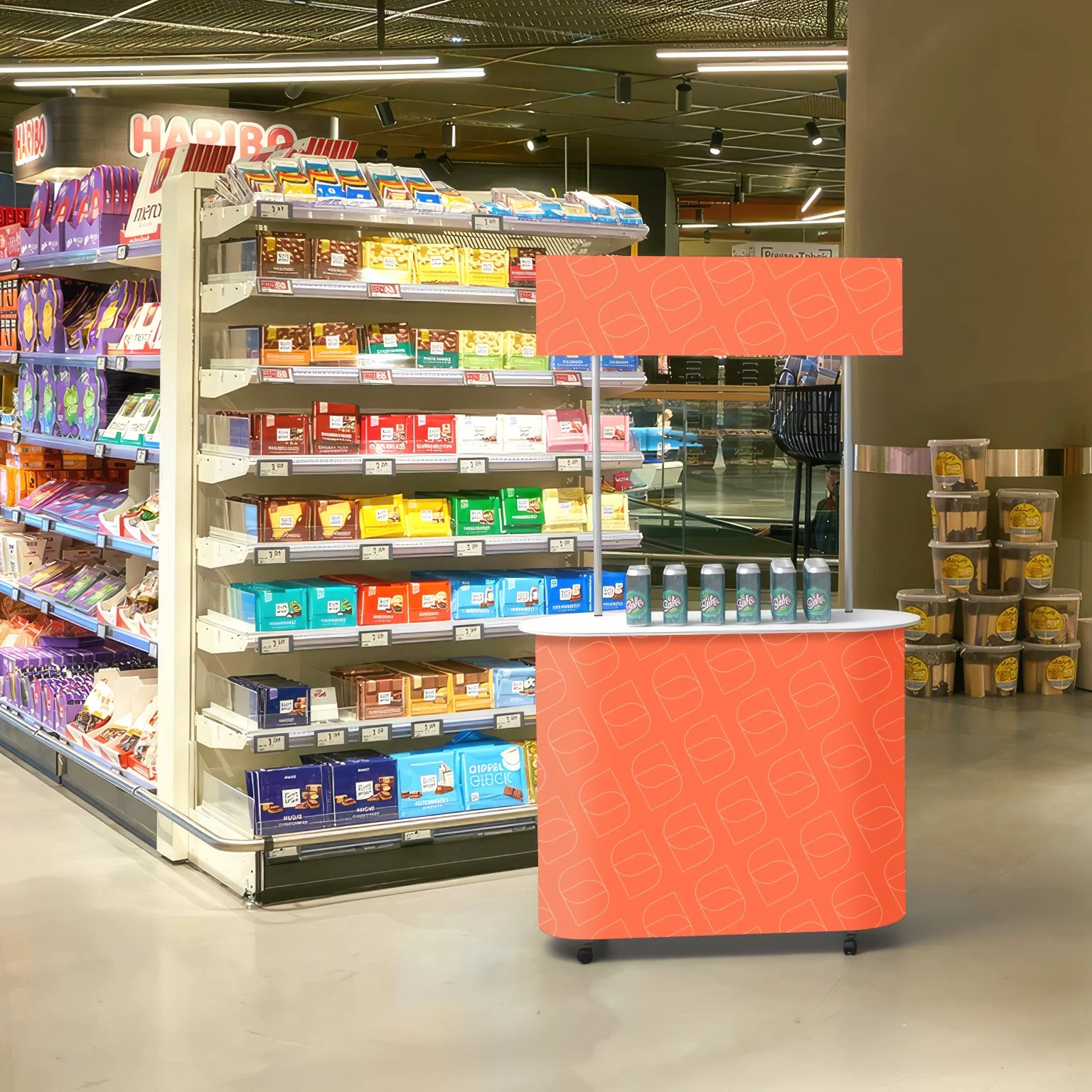 Chiosco di vendita di snack e bibite in un supermercato, con scatole di snack colorate sugli scaffali e bibite in lattina sul banco.