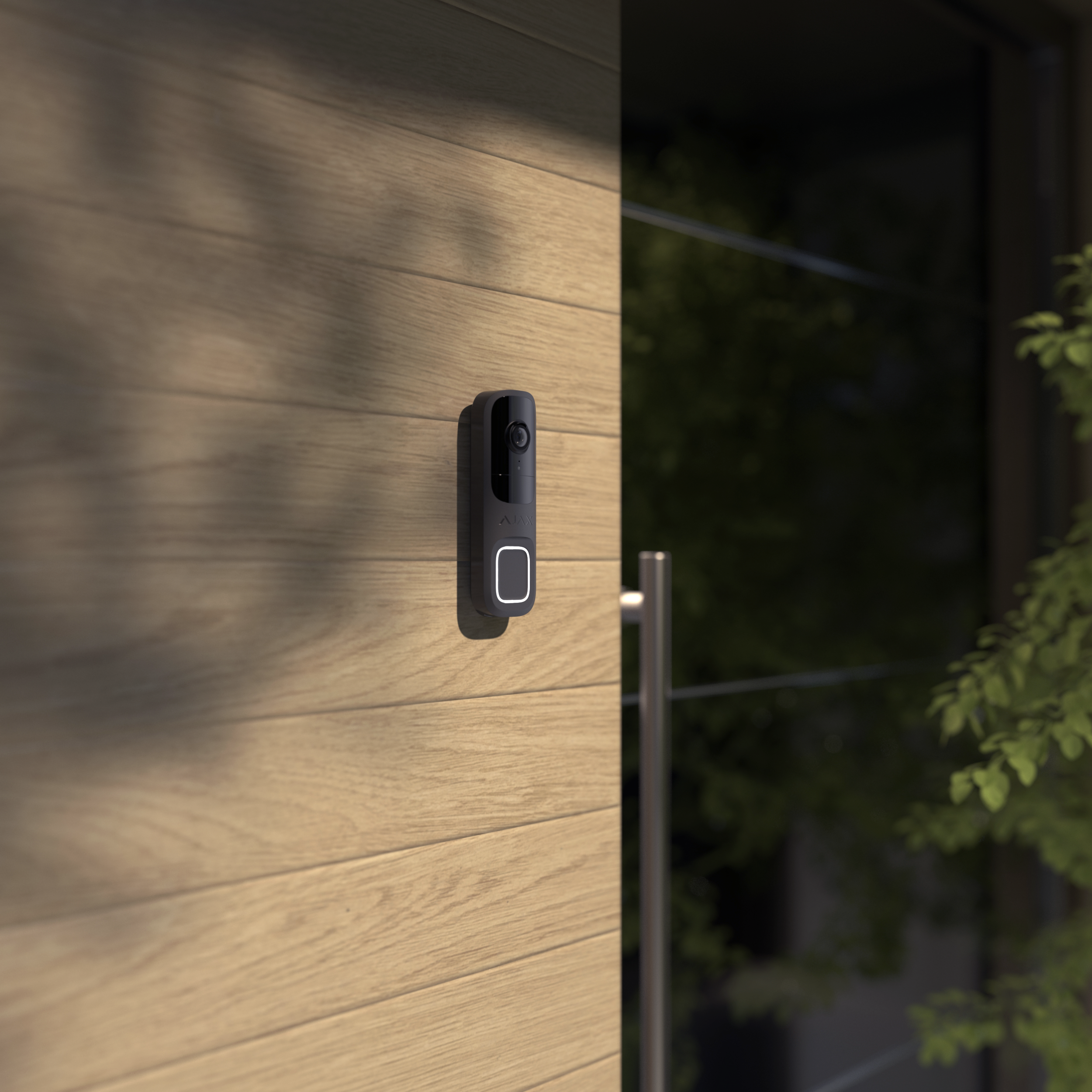 A modern doorbell with a camera mounted on a wooden exterior wall at nighttime, with some greenery visible in the background. part of a Complete Fire and Security System in Southampton, Hampshire.