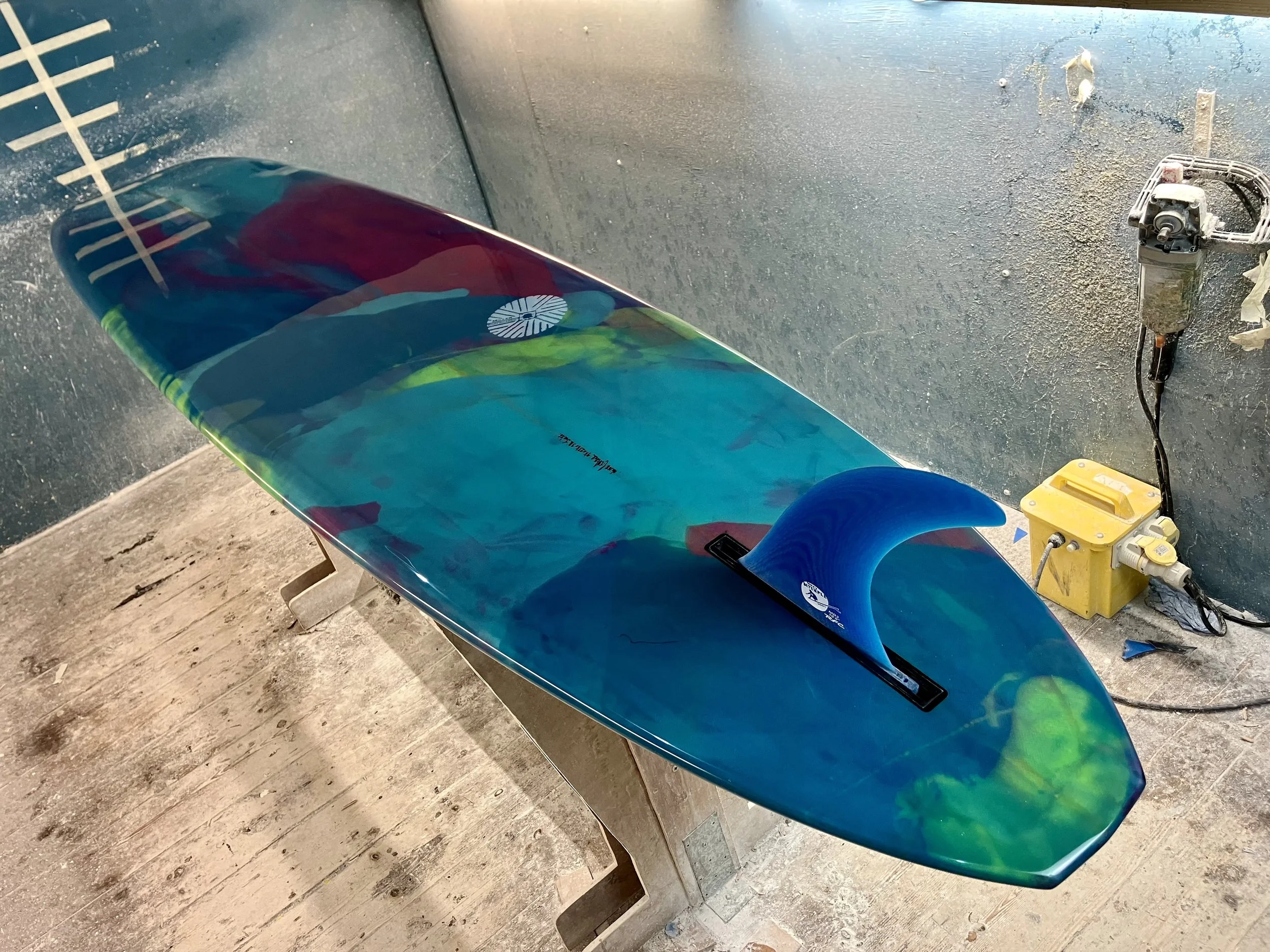 shine abstract resin tint surfboard longboard on a stand in a shaping bay