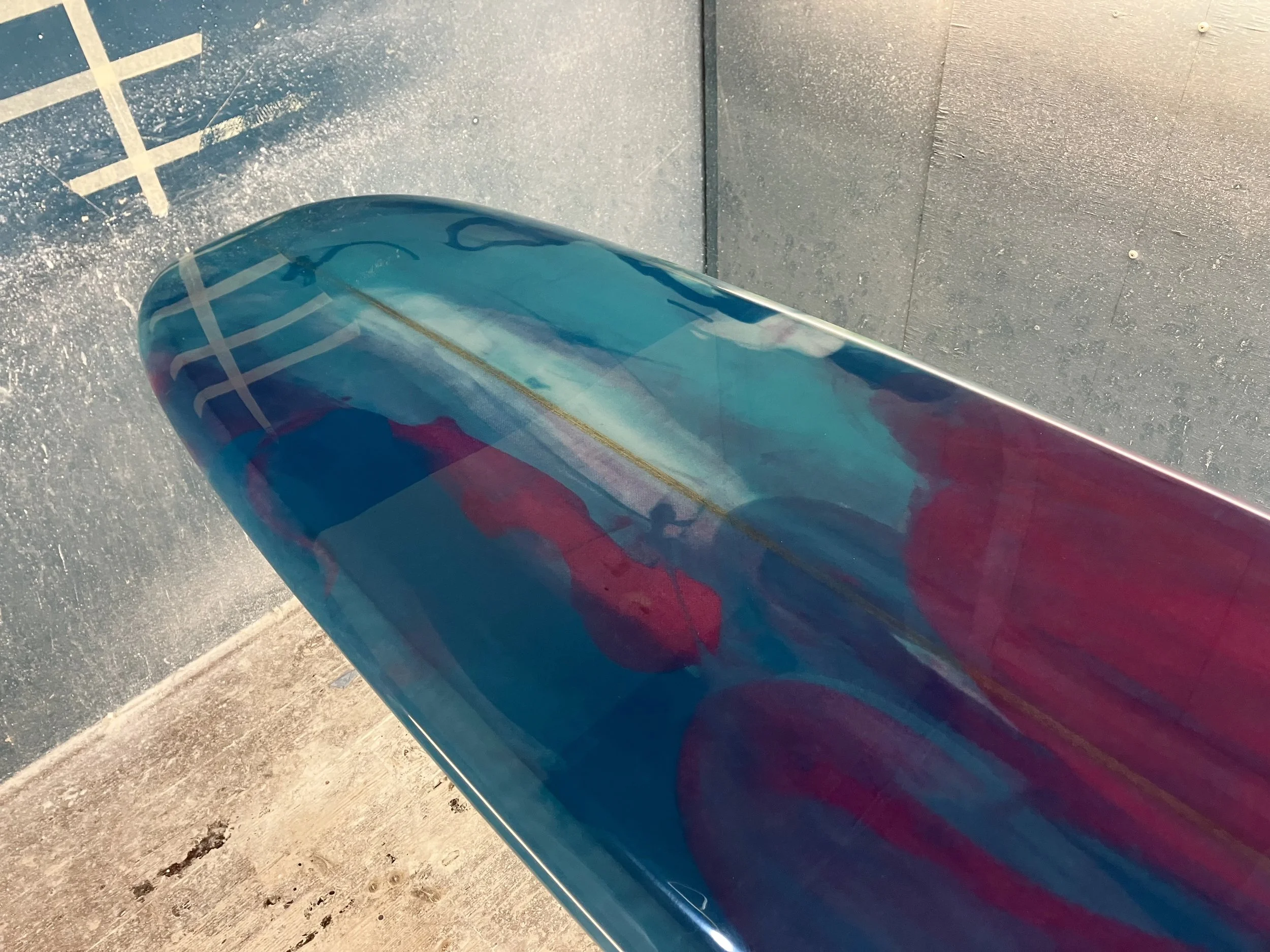 shine abstract resin tint surfboard longboard on a stand in a shaping bay