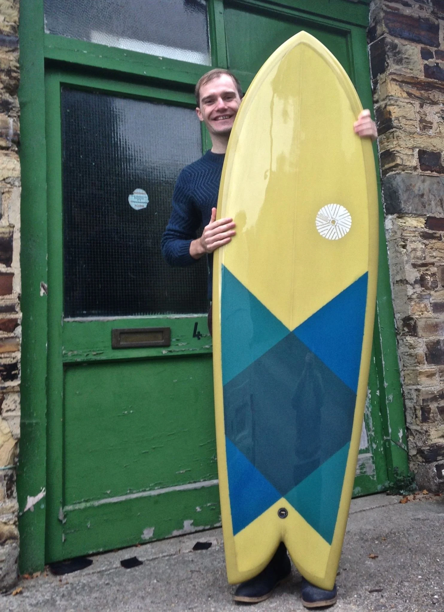 twin fin fish surfboard with yellow resin tint and coloured resin patches
