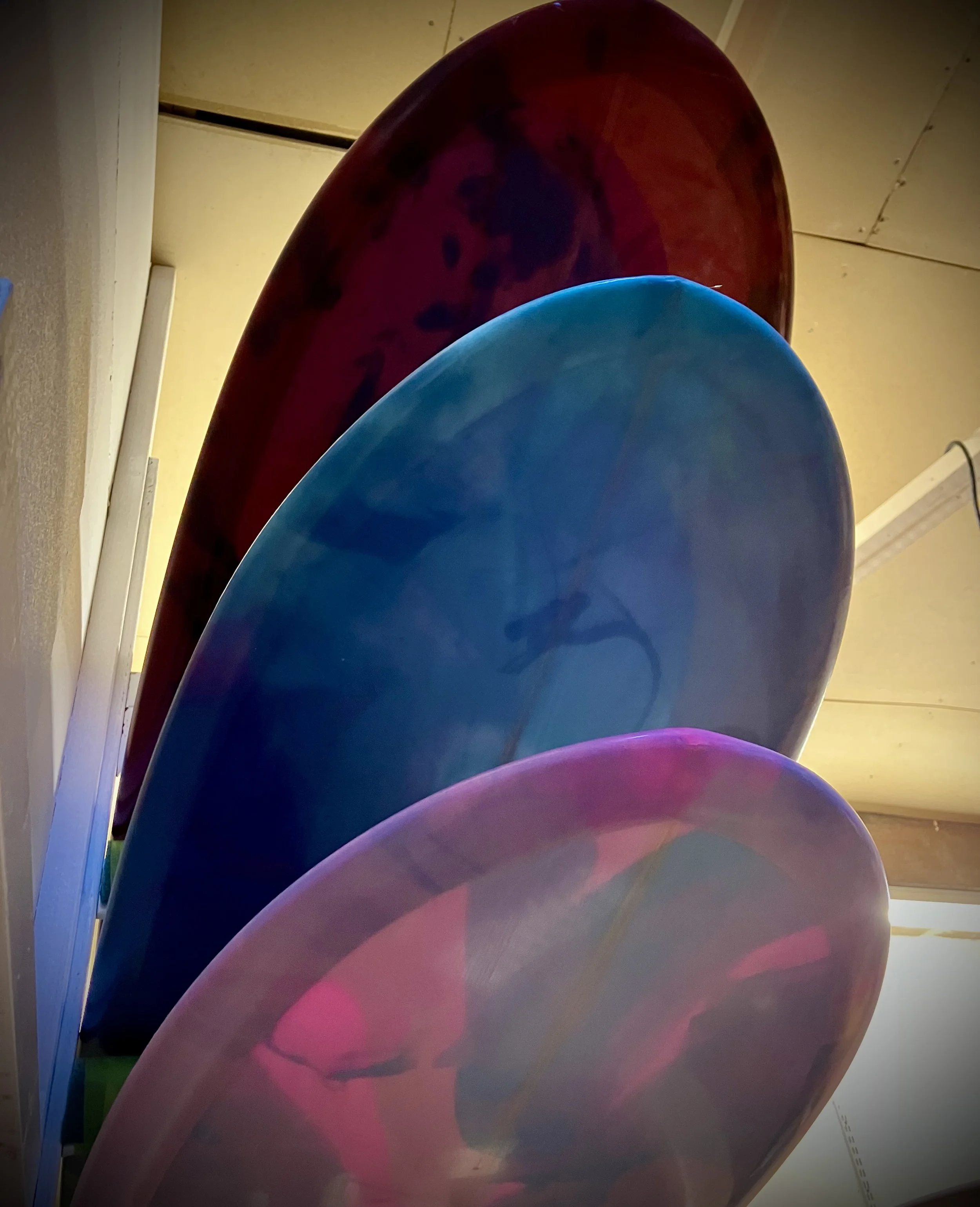 3 longboard Sliders lined up on surfboard rack