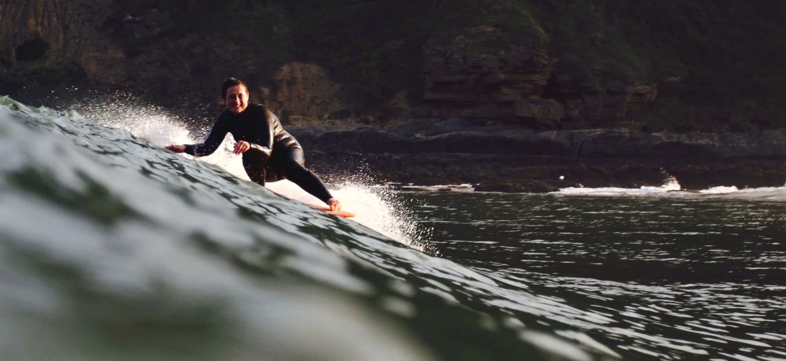 female surfer hanging 5 and smiling whilst riding a longboard