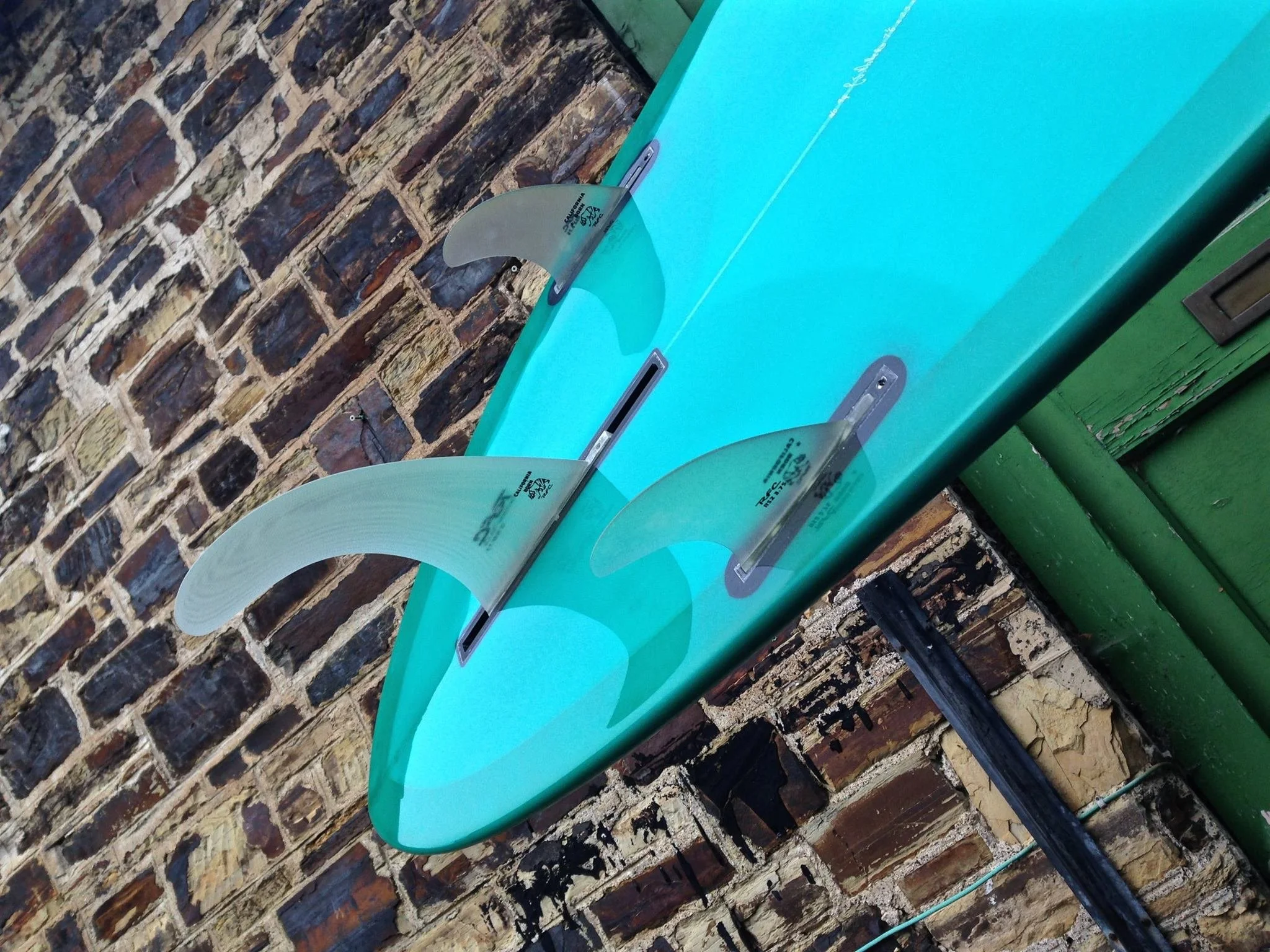 tail of carpet surfboard with turquoise resin tint