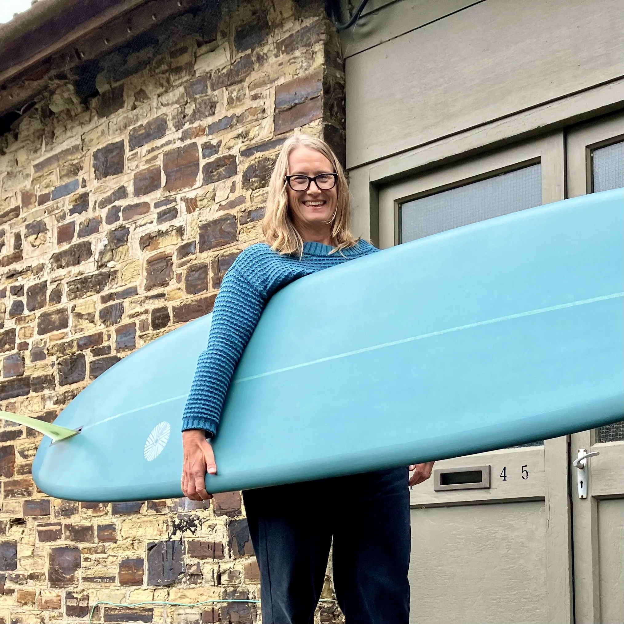 customer with teal coloured longboard surfboard