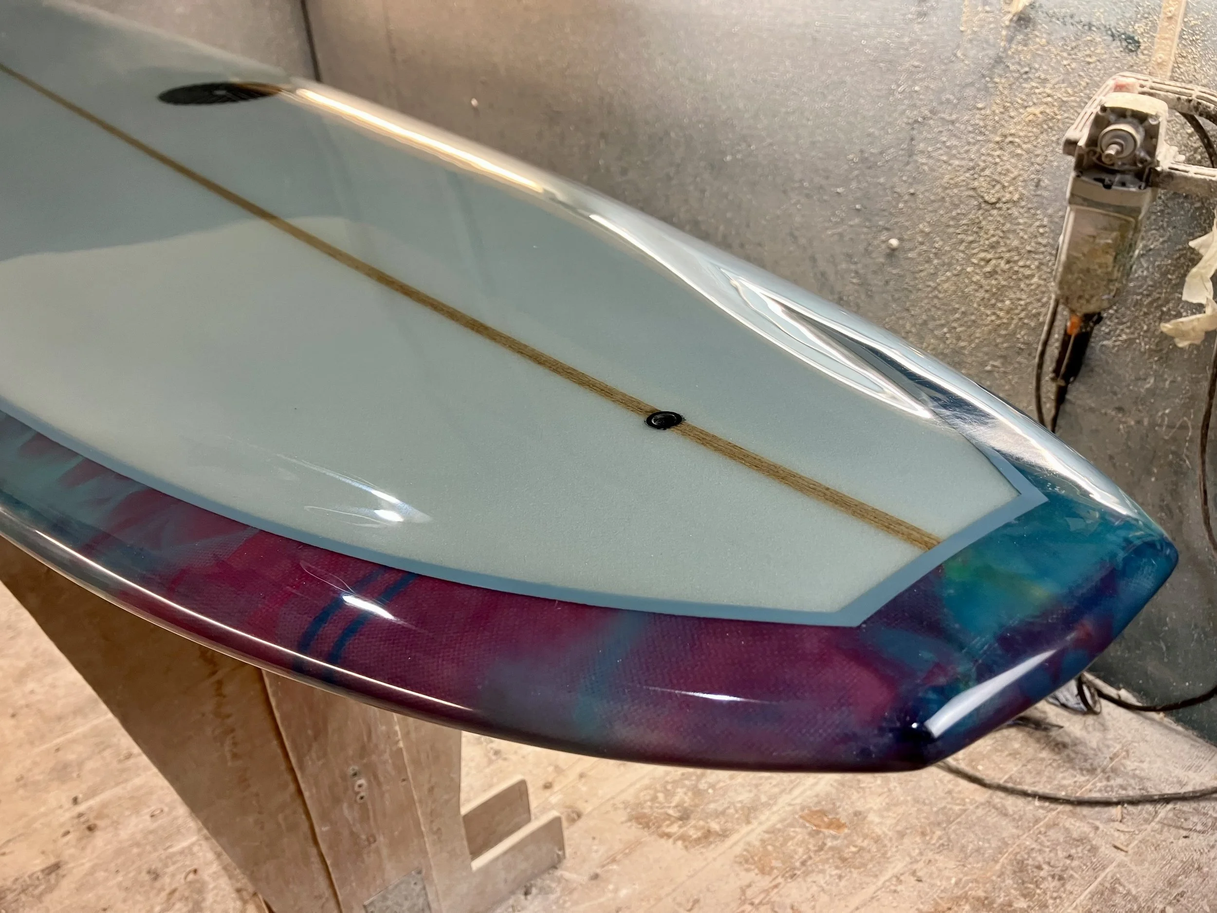shine abstract resin tint surfboard longboard on a stand in a shaping bay