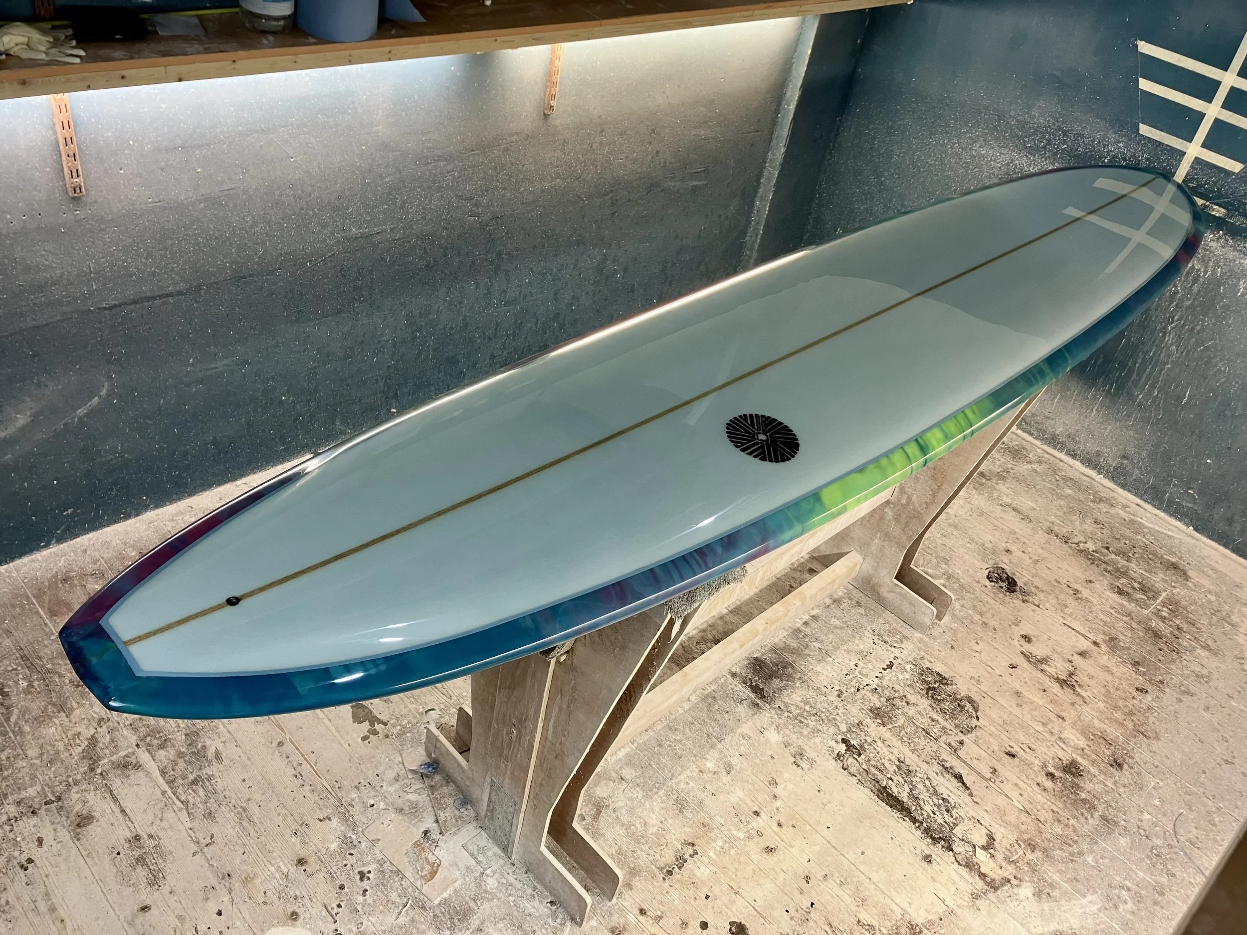 shine abstract resin tint surfboard longboard on a stand in a shaping bay