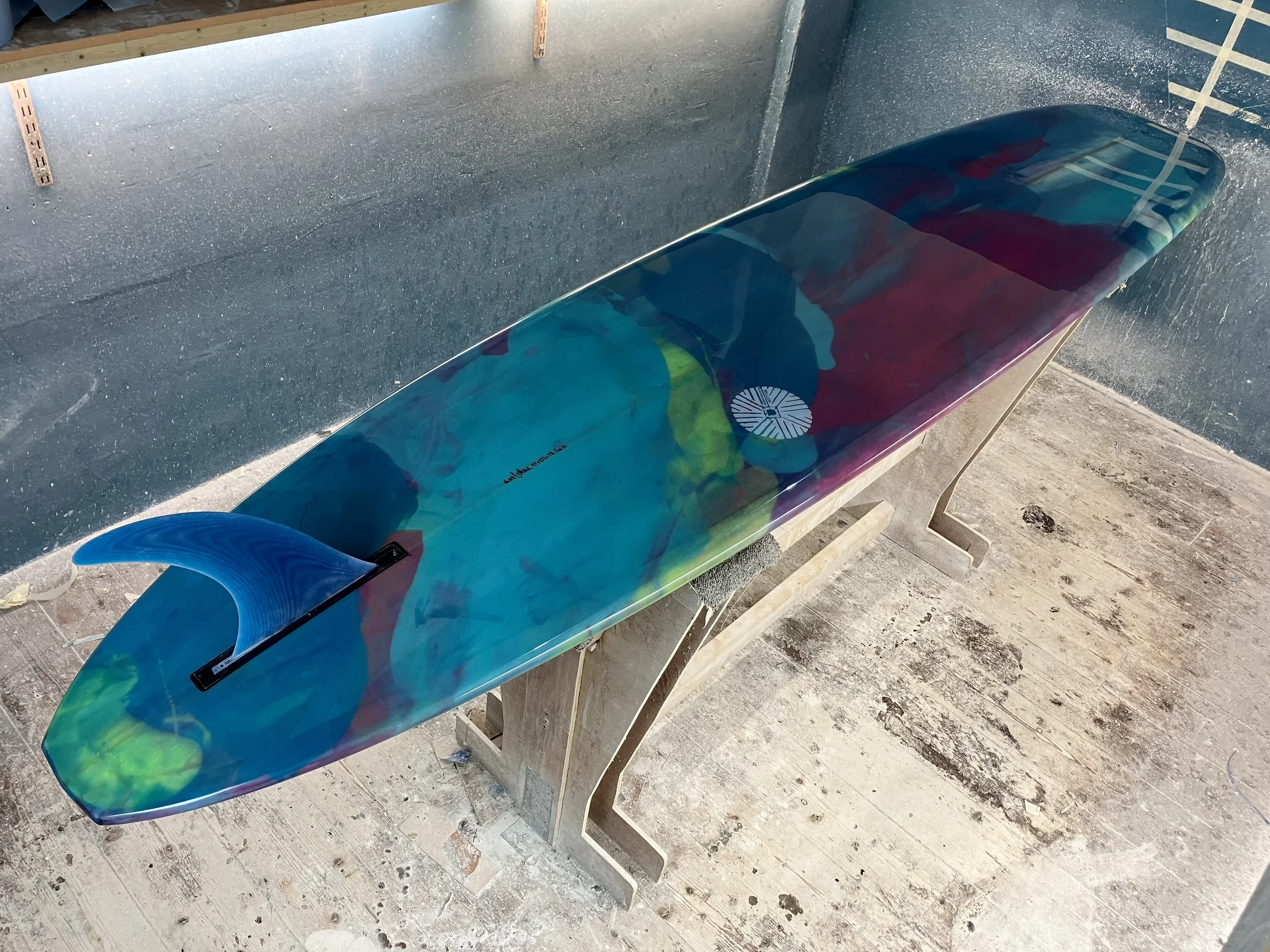 shine abstract resin tint surfboard longboard on a stand in a shaping bay