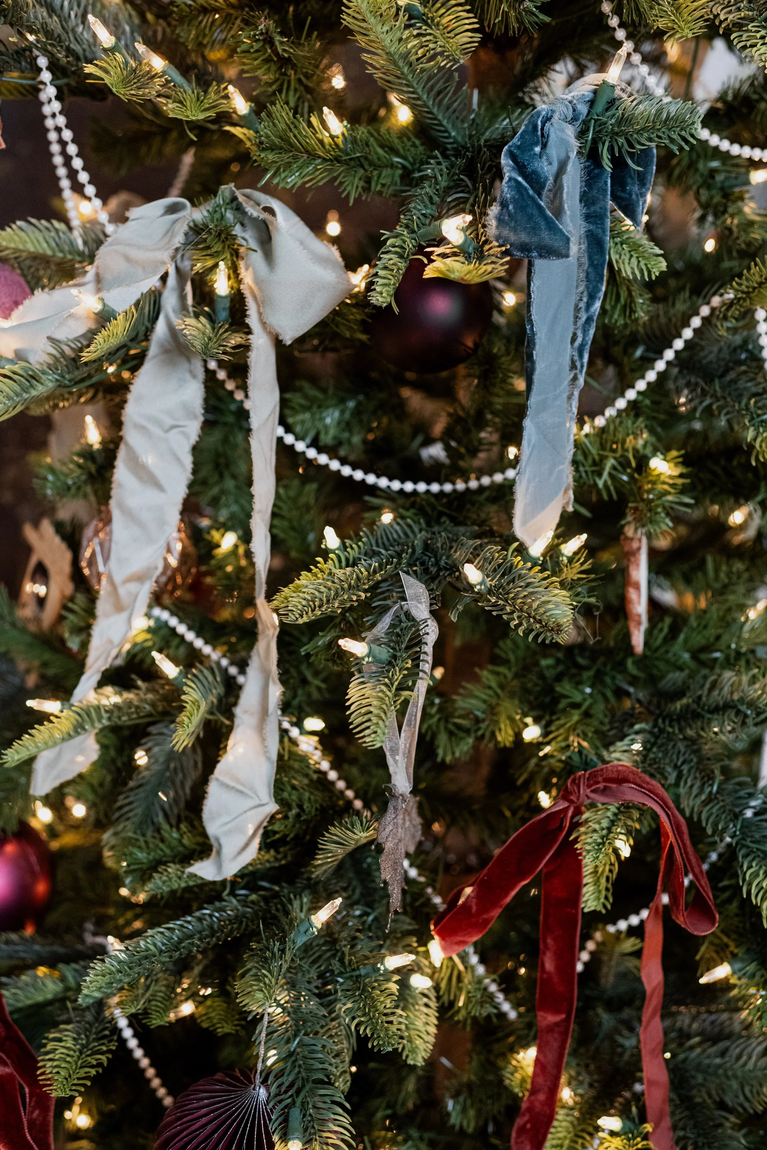 Close-up of a decorated Christmas tree with ribbons, string lights, and ornaments.